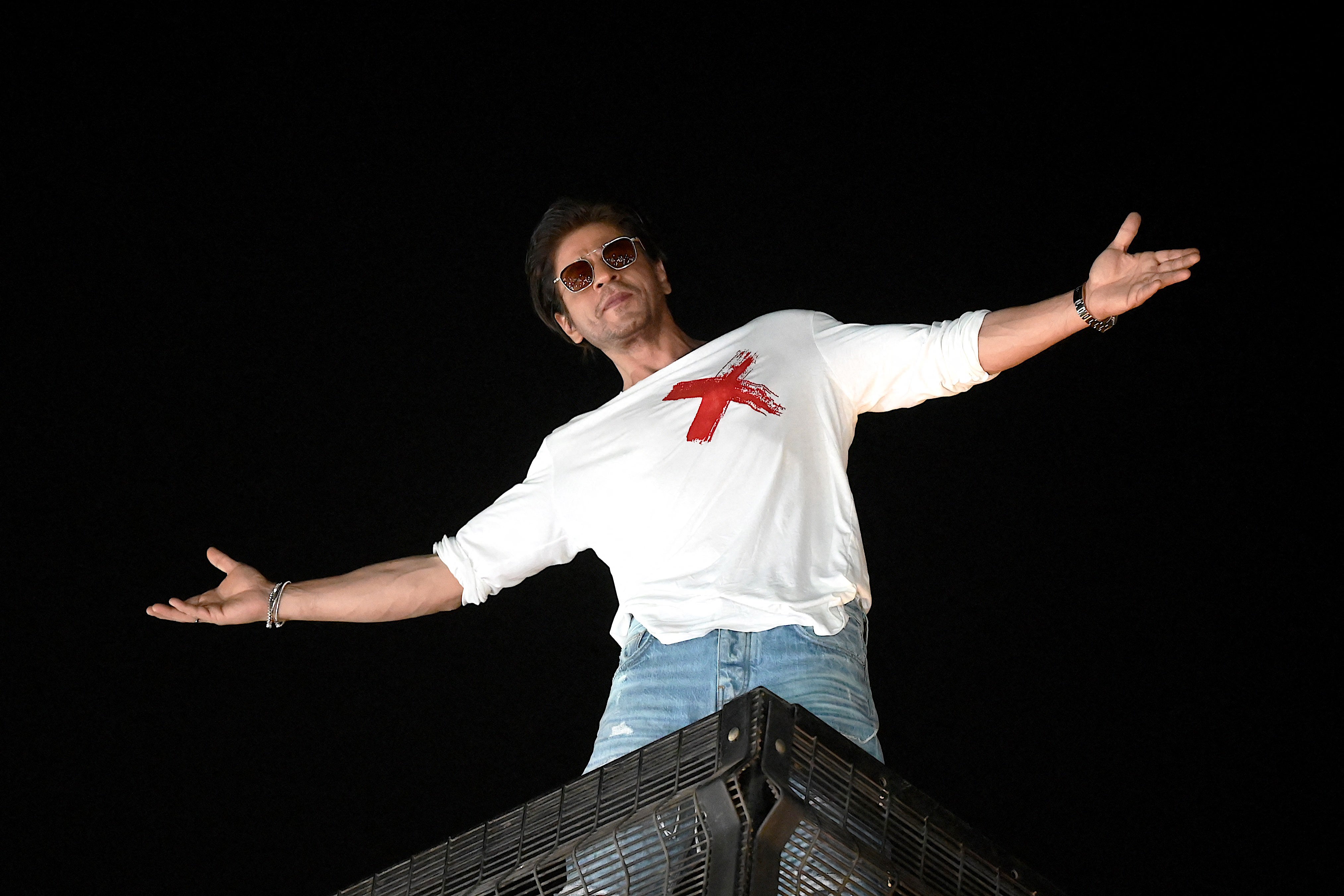 Bollywood actor Shah Rukh Khan strikes his iconic pose as he greets fans during his 58th birthday celebrations at his residence in Mumbai