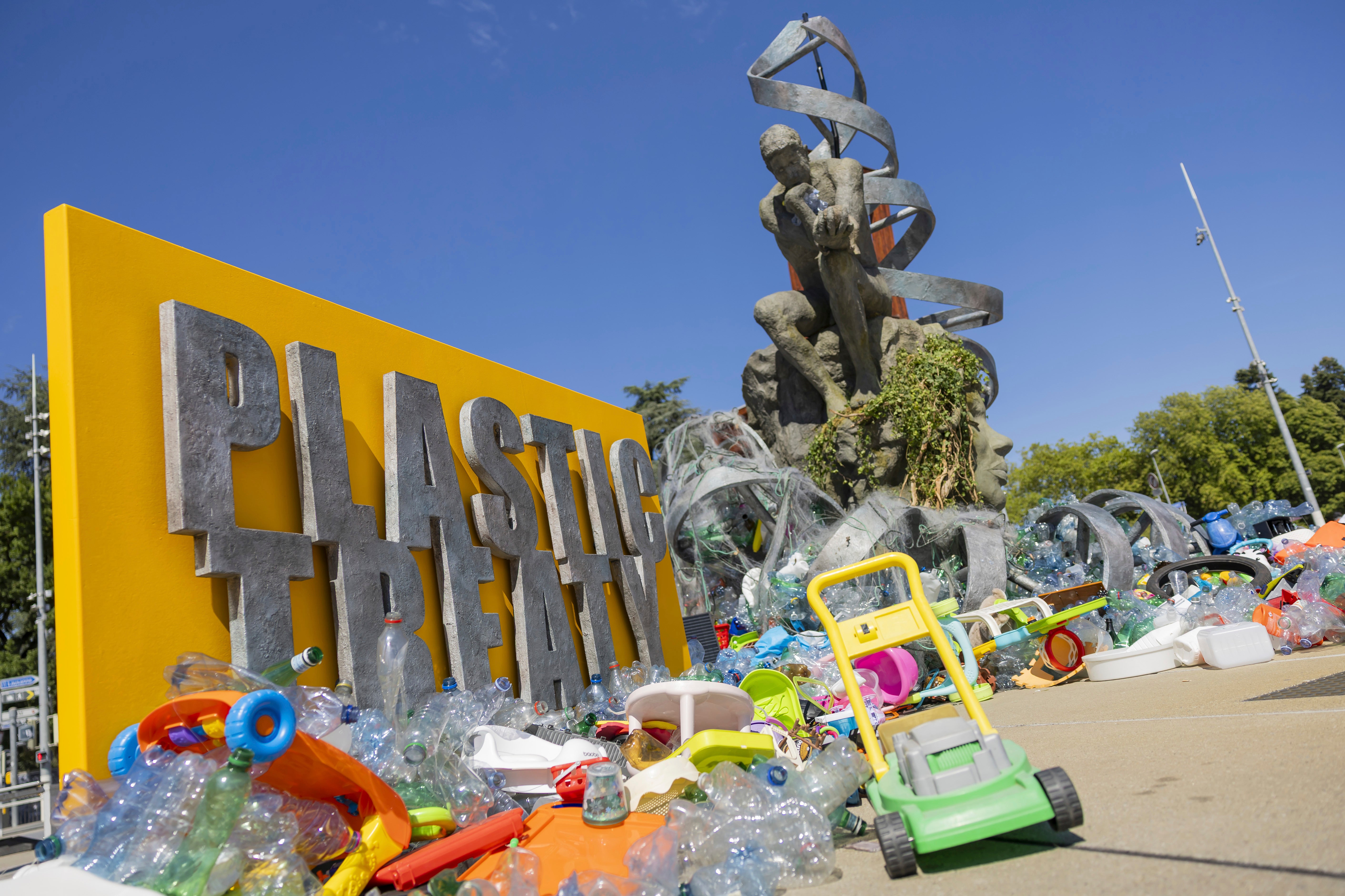 Plastic items are seen next to an artwork by Canadian artist and activist Benjamin Von Wong, titled 'The Thinker's Burden'