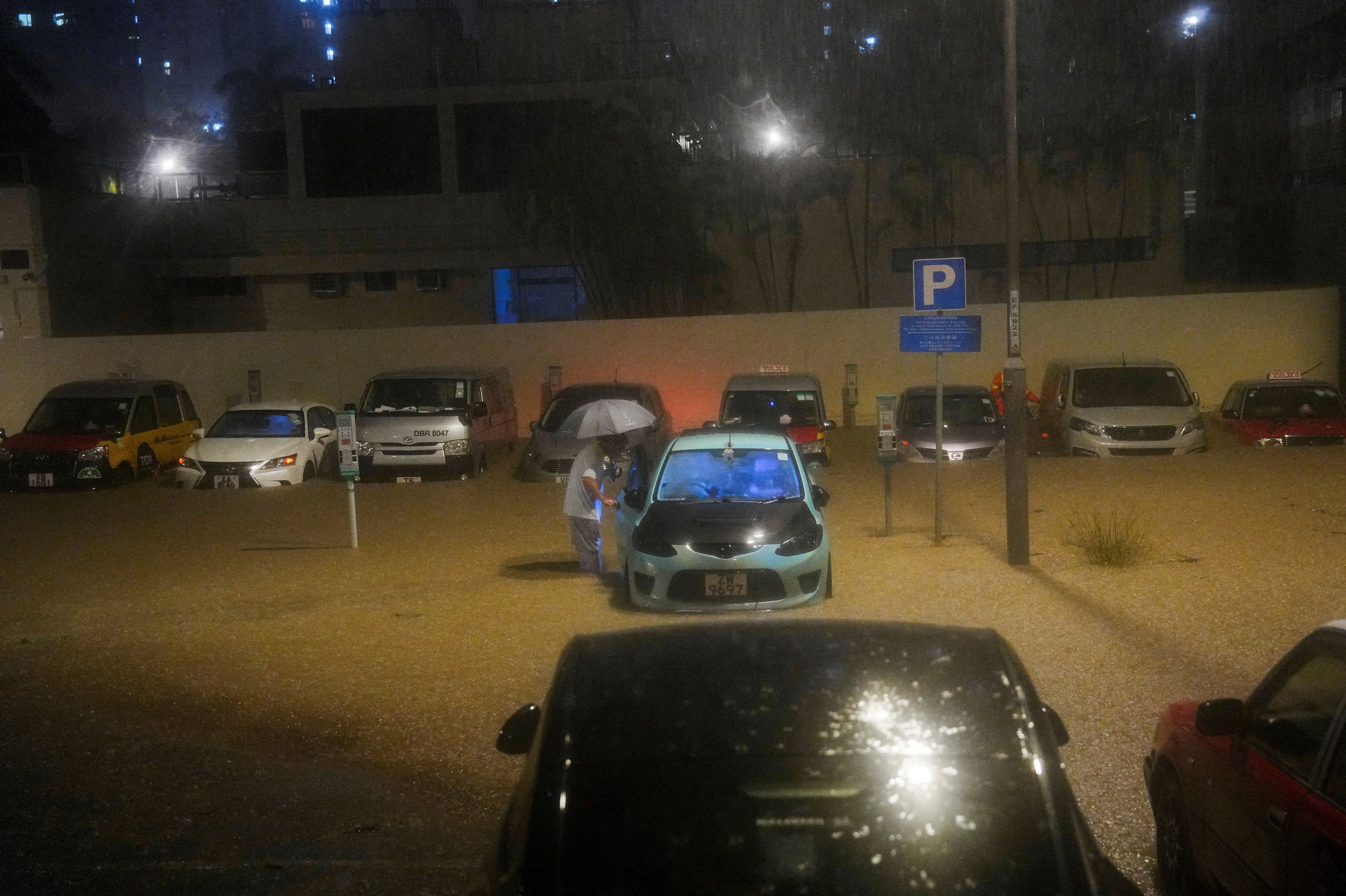 A car owner checks his vehicle partially submerged in a flooded area during heavy rains in Hong Kong on 5 August 2025