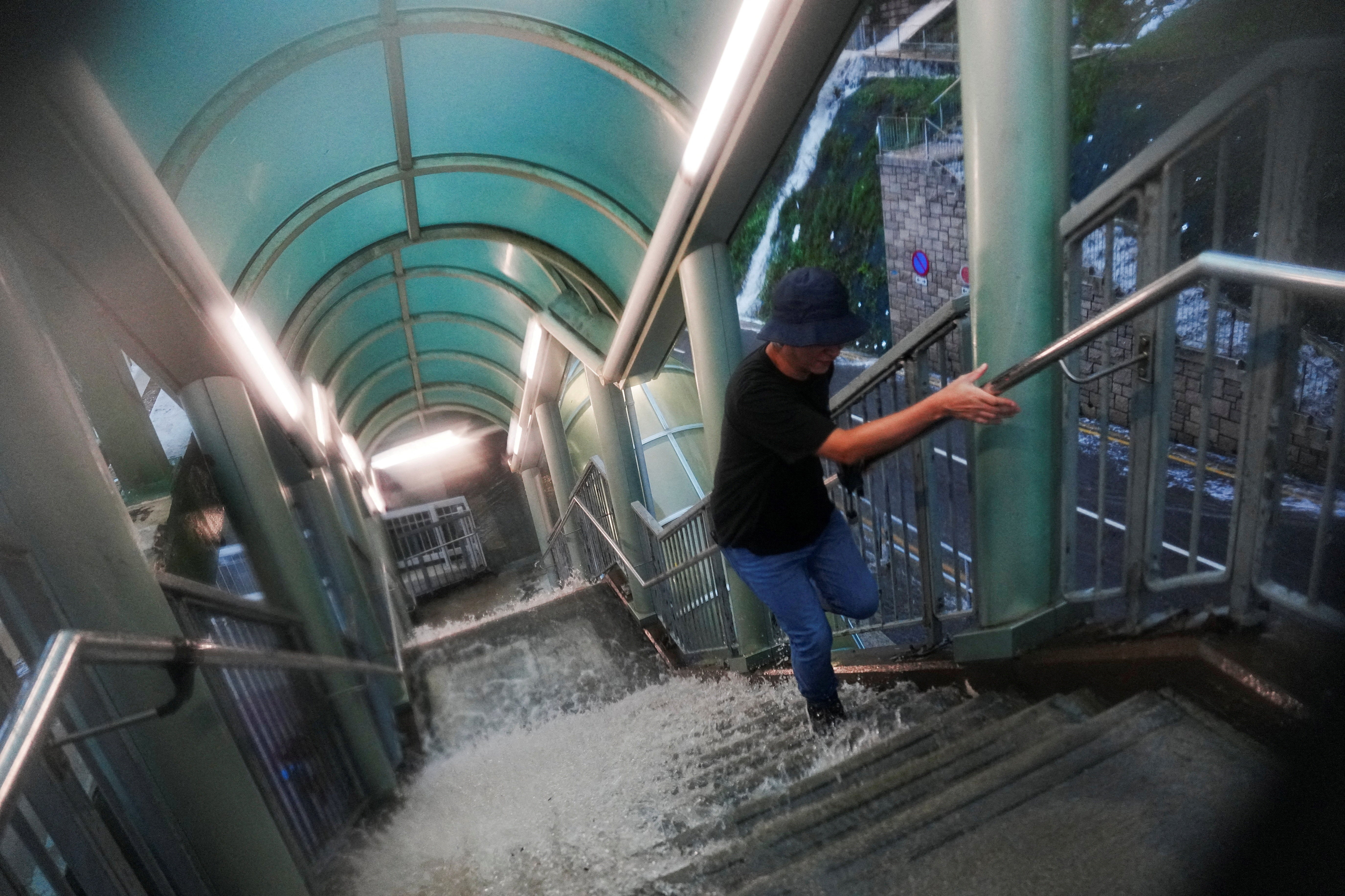 A pedestrian walks past a flooded stairs outside a hospital during heavy rains, in Hong Kong, 5 August 2025