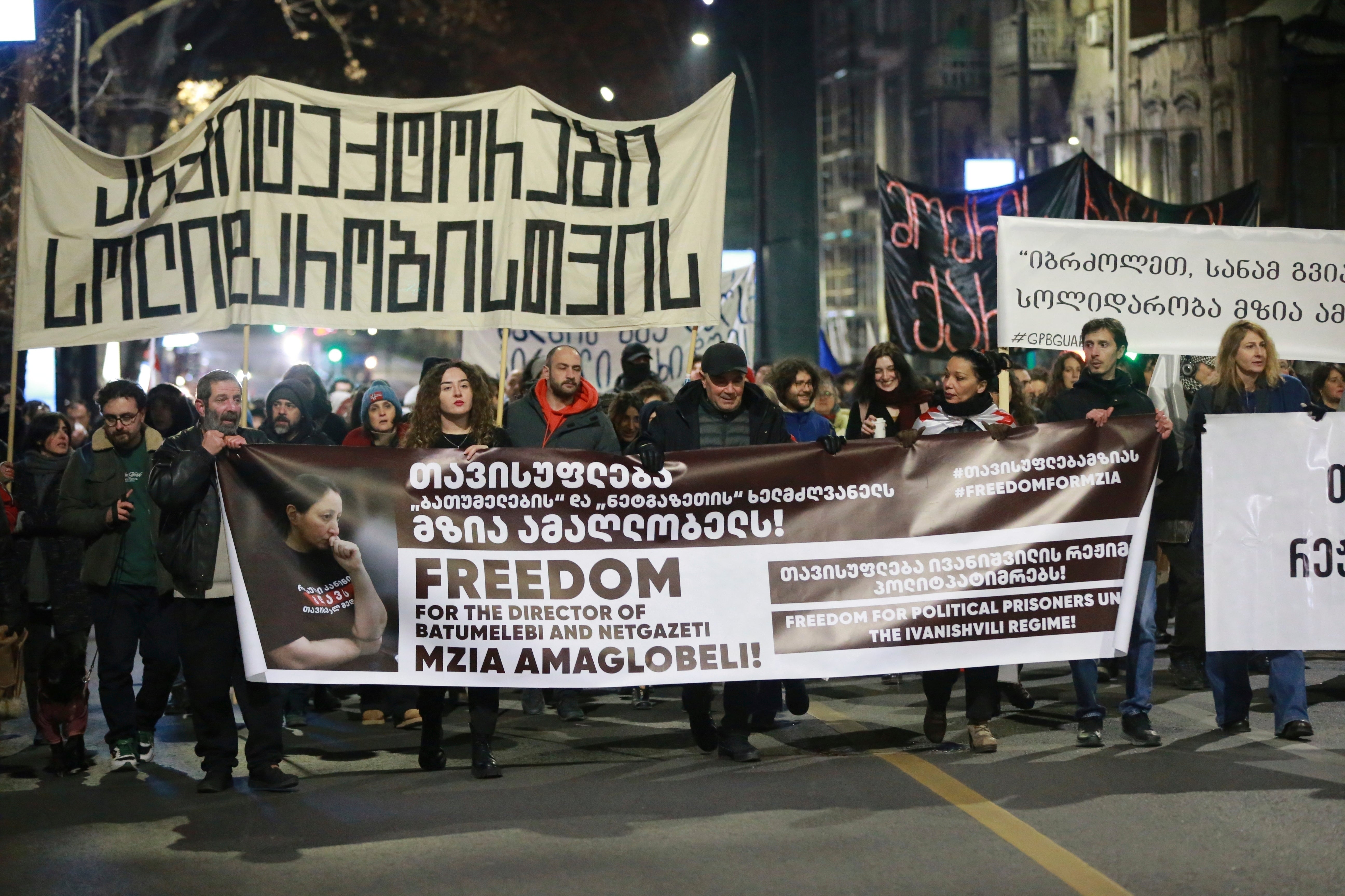 Protesters hold banners calling for the release of jailed journalist Mzia Amaghlobeli as they march through the streets in Tbilisi, Georgia