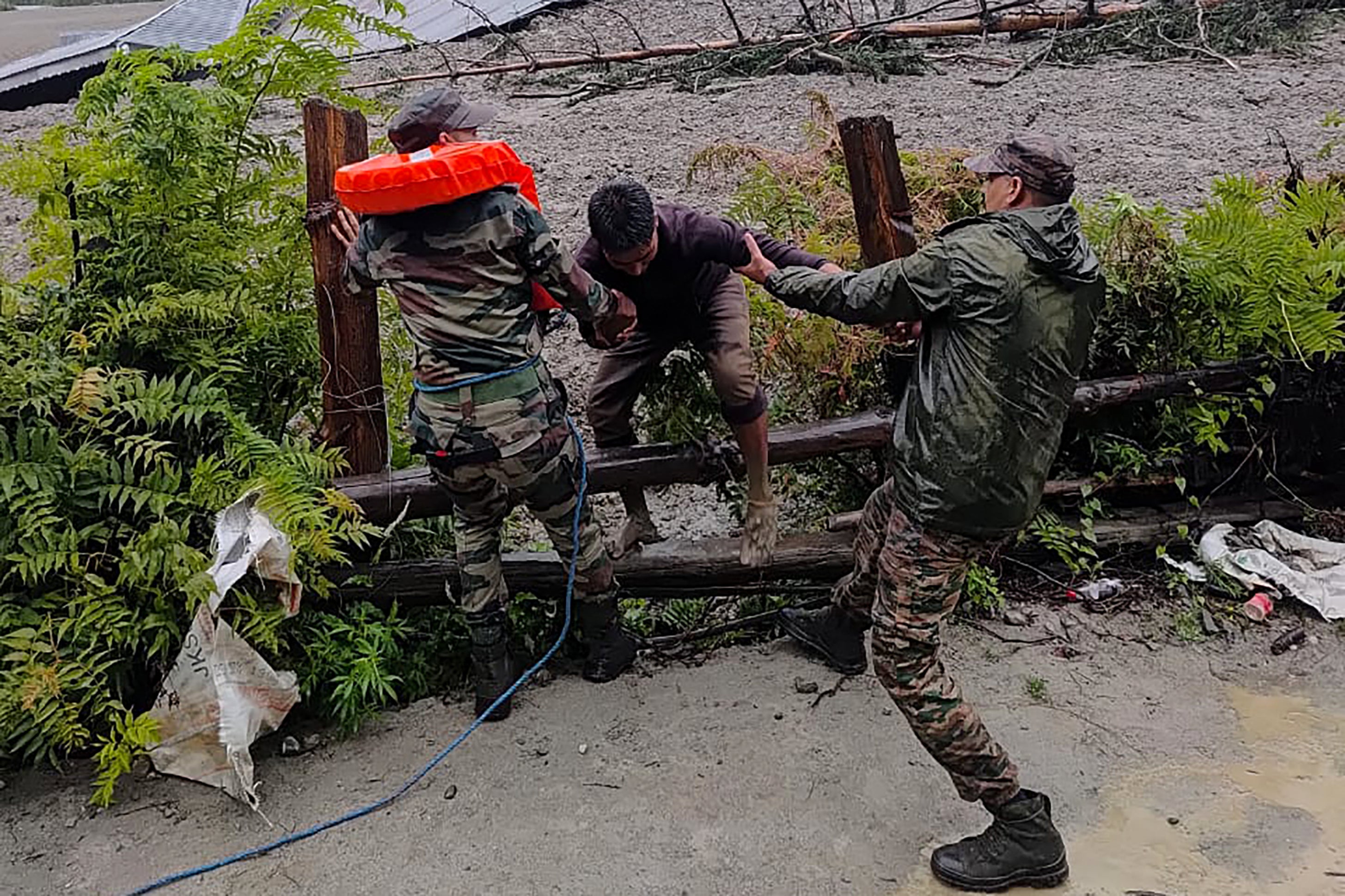 Security personnel rescue a local resident from dense sludge after a cloudburst caused a massive mudslide and flash flood in Uttarakhand, India, on 5 August 2025