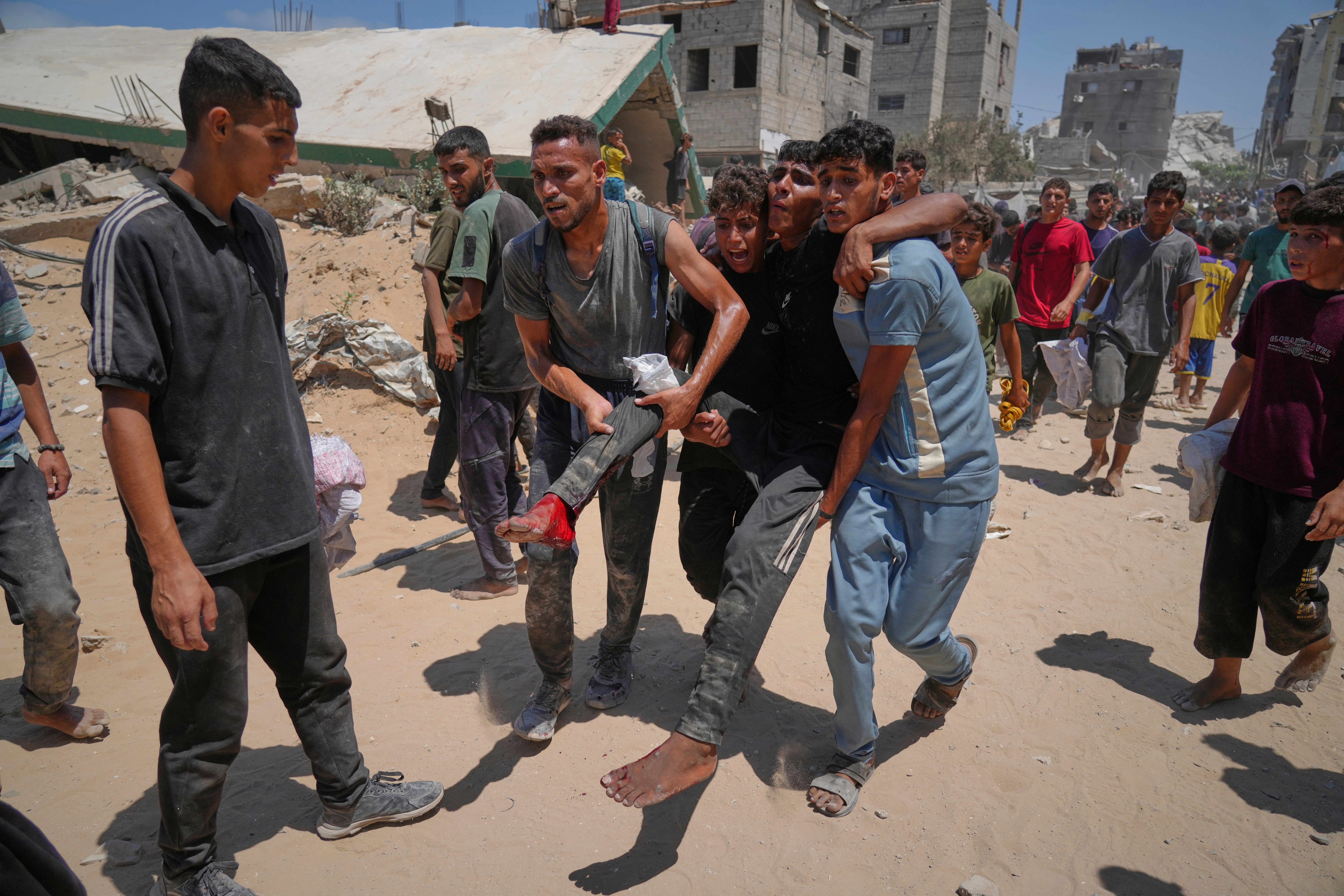 Palestinians carry a man injured while rushing to collect humanitarian aid in the northern Gaza Strip on Thursday 7 August