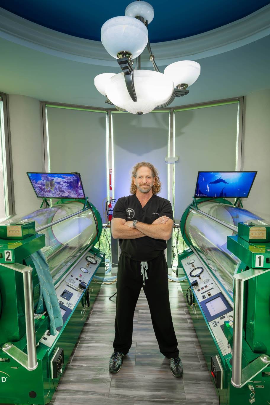 Dr. Joseph Dituri stands beside two hyperbaric oxygen chambers, which mimic the high-pressure environments under the sea and which his biomedical research suggests might help people live longer if entered into periodically throughout one's life