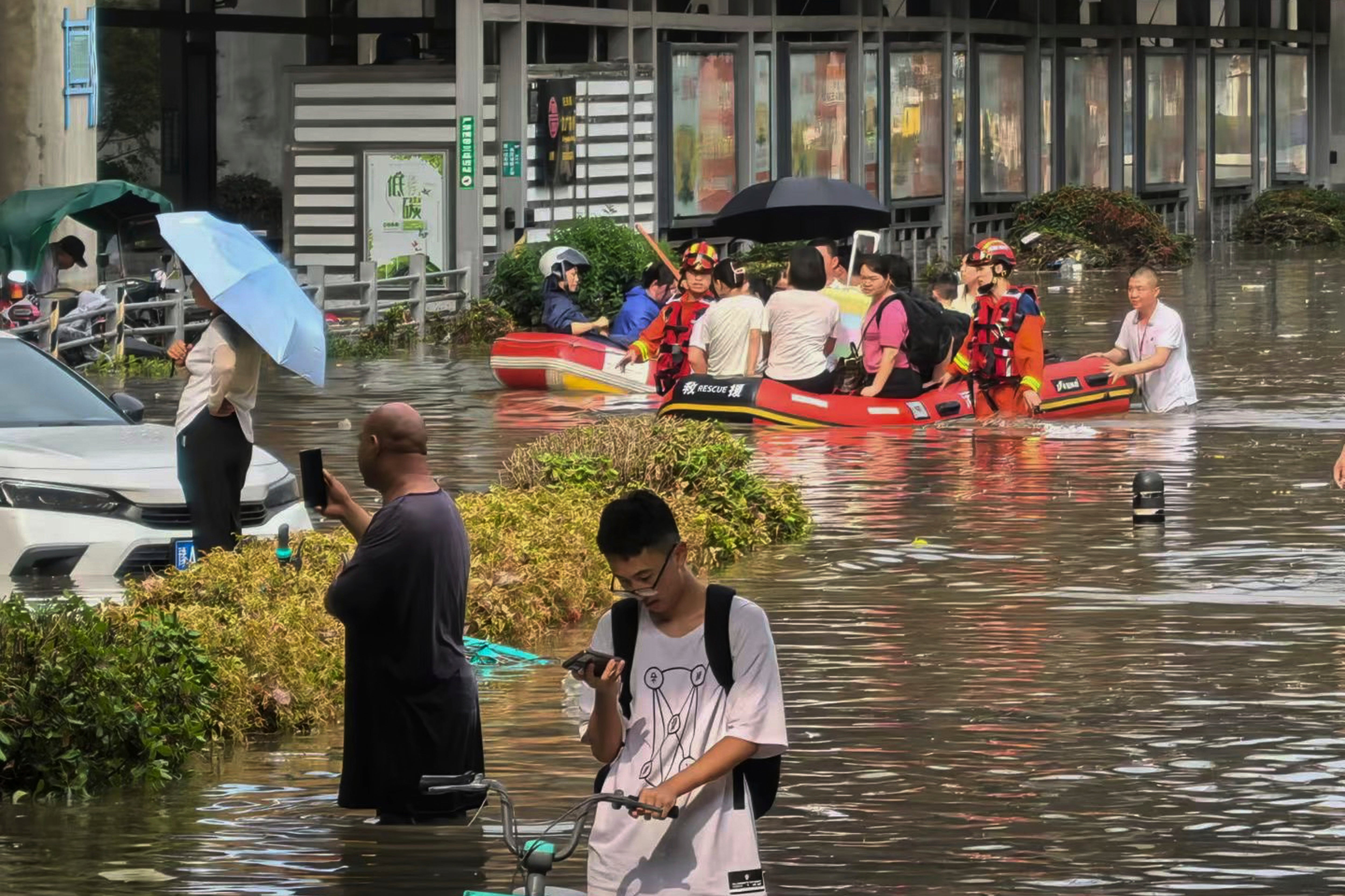 Rescuers use inflatable boats to ferry people across a flooded road in Zhengzhou