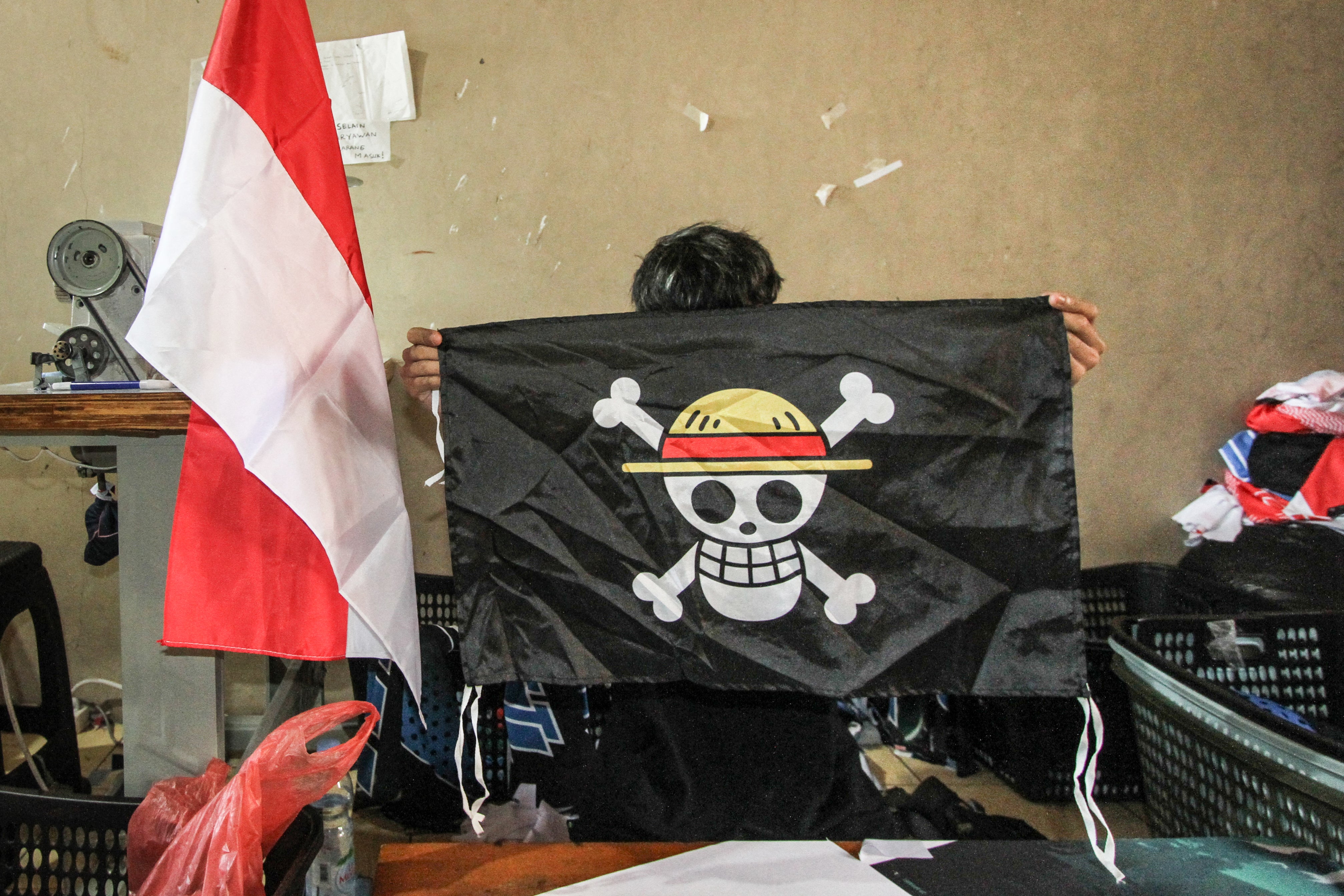 A worker holds a replica of the pirate flag from Japanese anime 'One Piece'