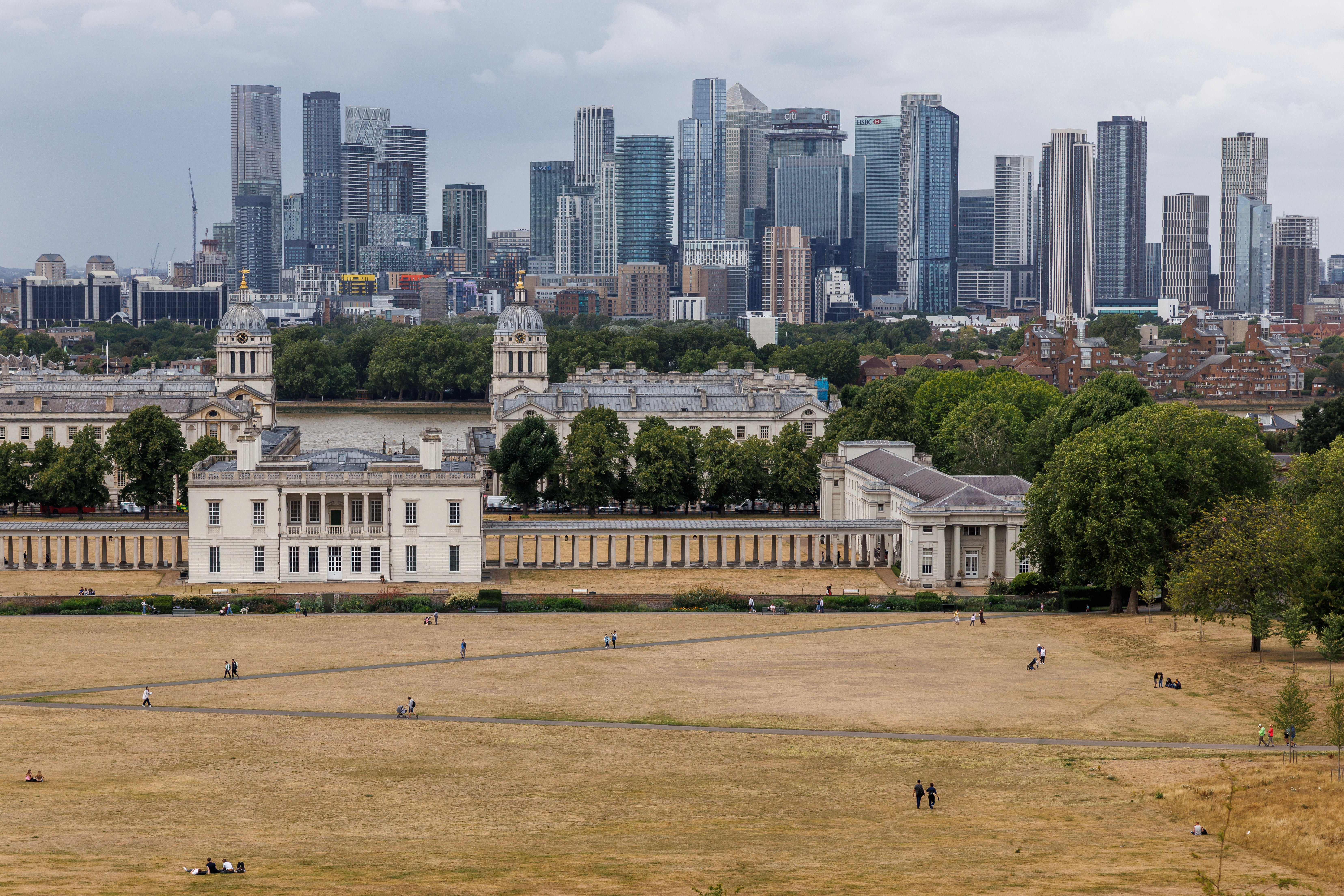 People walk through dried grass in Greenwich Park