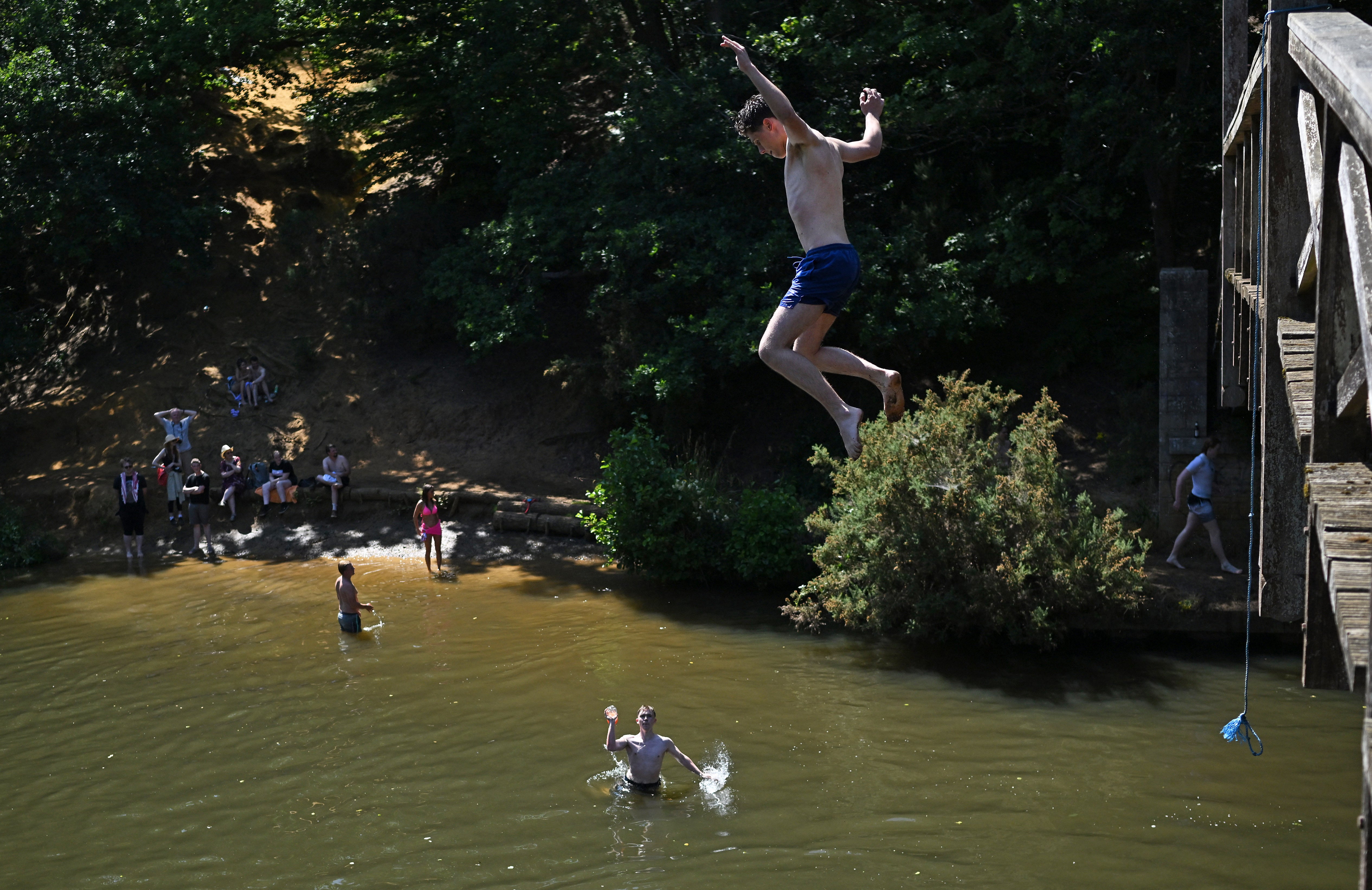 Teenagers cool off by leaping from the Wey footbridge into the River Wey, near Guildford
