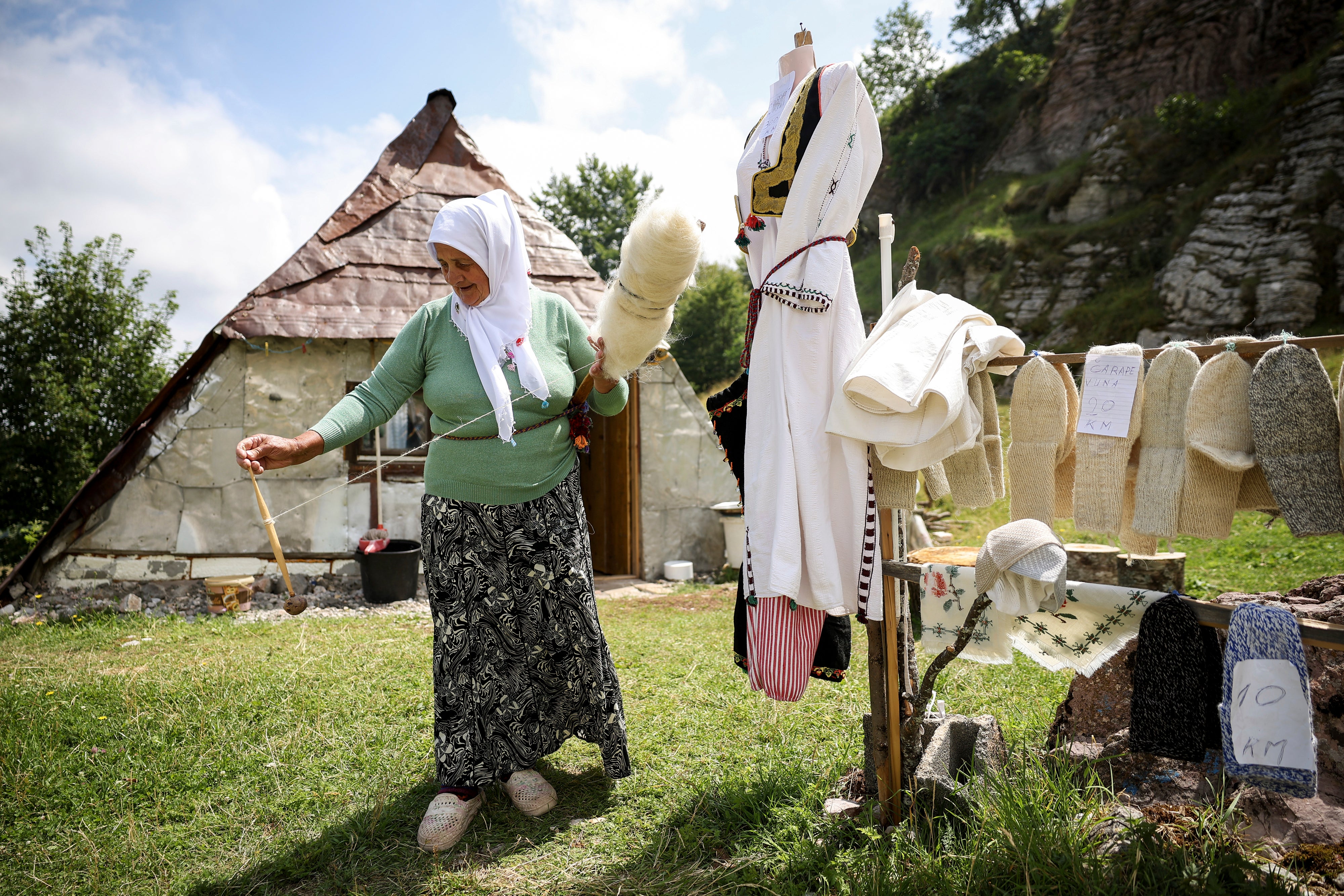 A Bosnian Muslim woman prepares wool that she later knits into sweaters or socks and sells to tourists in Umoljani village on Bjelasnica mountain near Sarajevo, Bosnia, Tuesday, Aug. 5, 2025. (AP Photo/Armin Durgut)