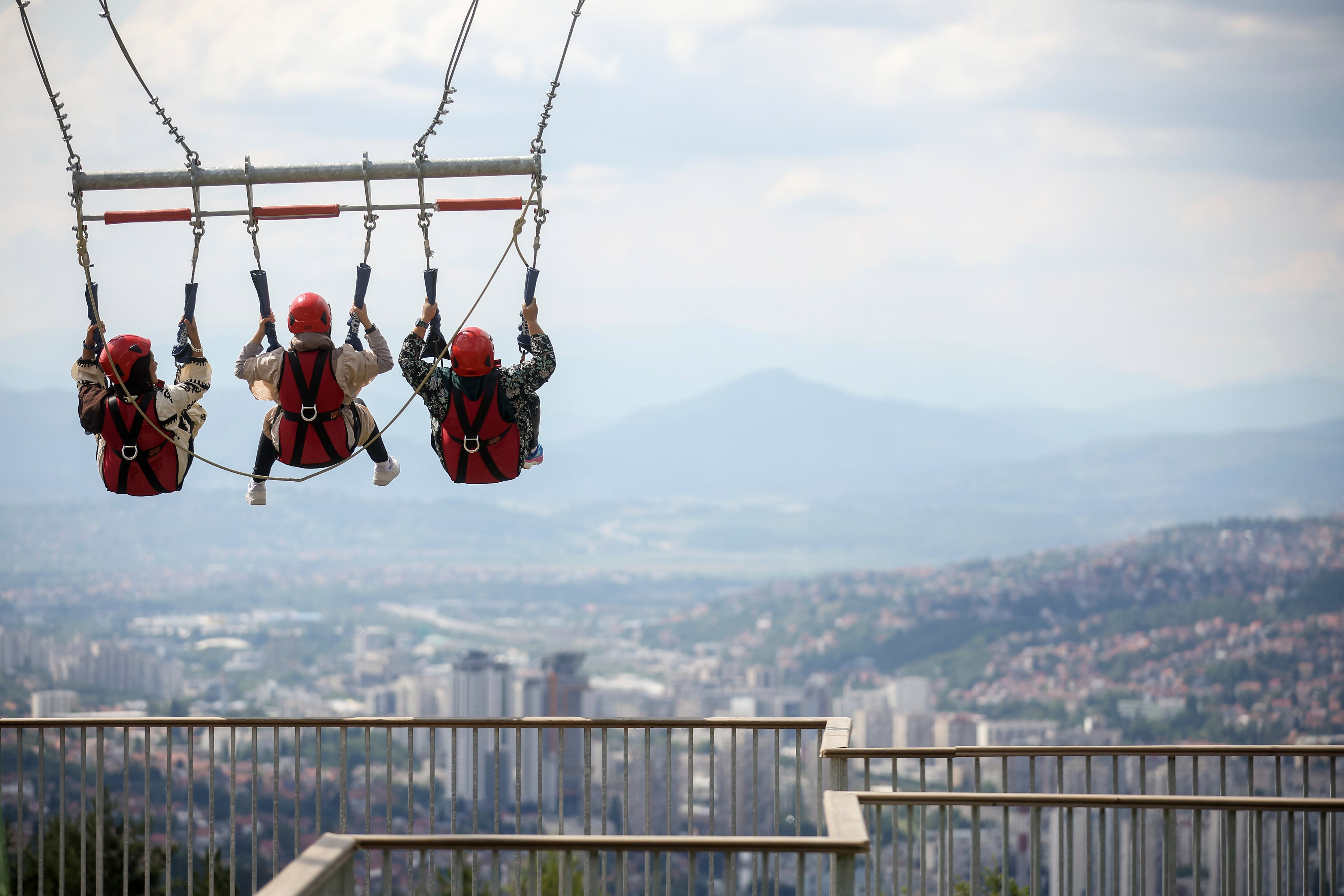 Tourists enjoy a giant swing overlooking the city on Trebevic mountain near Sarajevo, Bosnia, Tuesday, Aug. 5, 2025. (AP Photo/Armin Durgut)