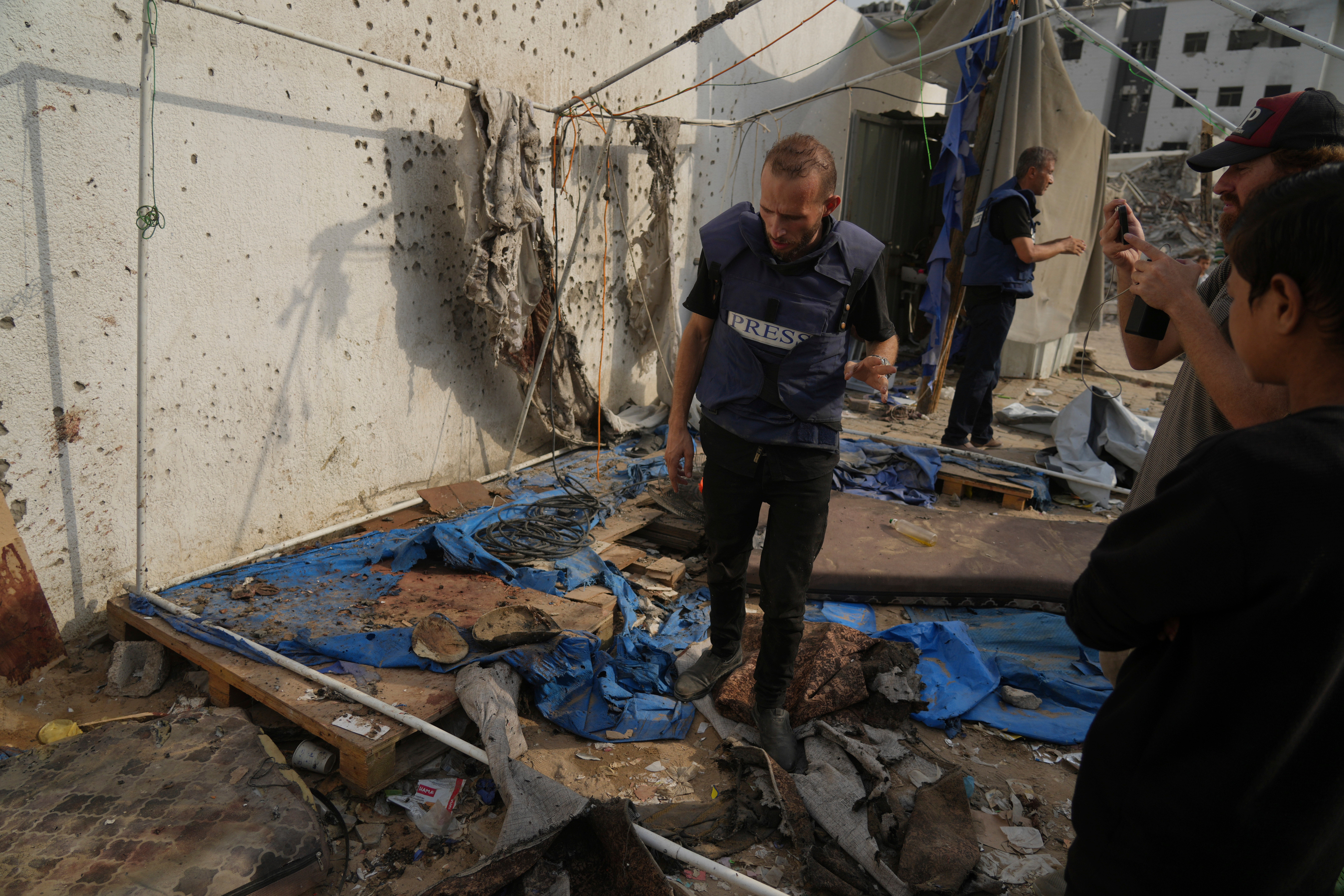 Palestinians inspect the destroyed tent where journalists, were killed by an Israeli airstrike outside the Gaza City's Shifa hospital complex