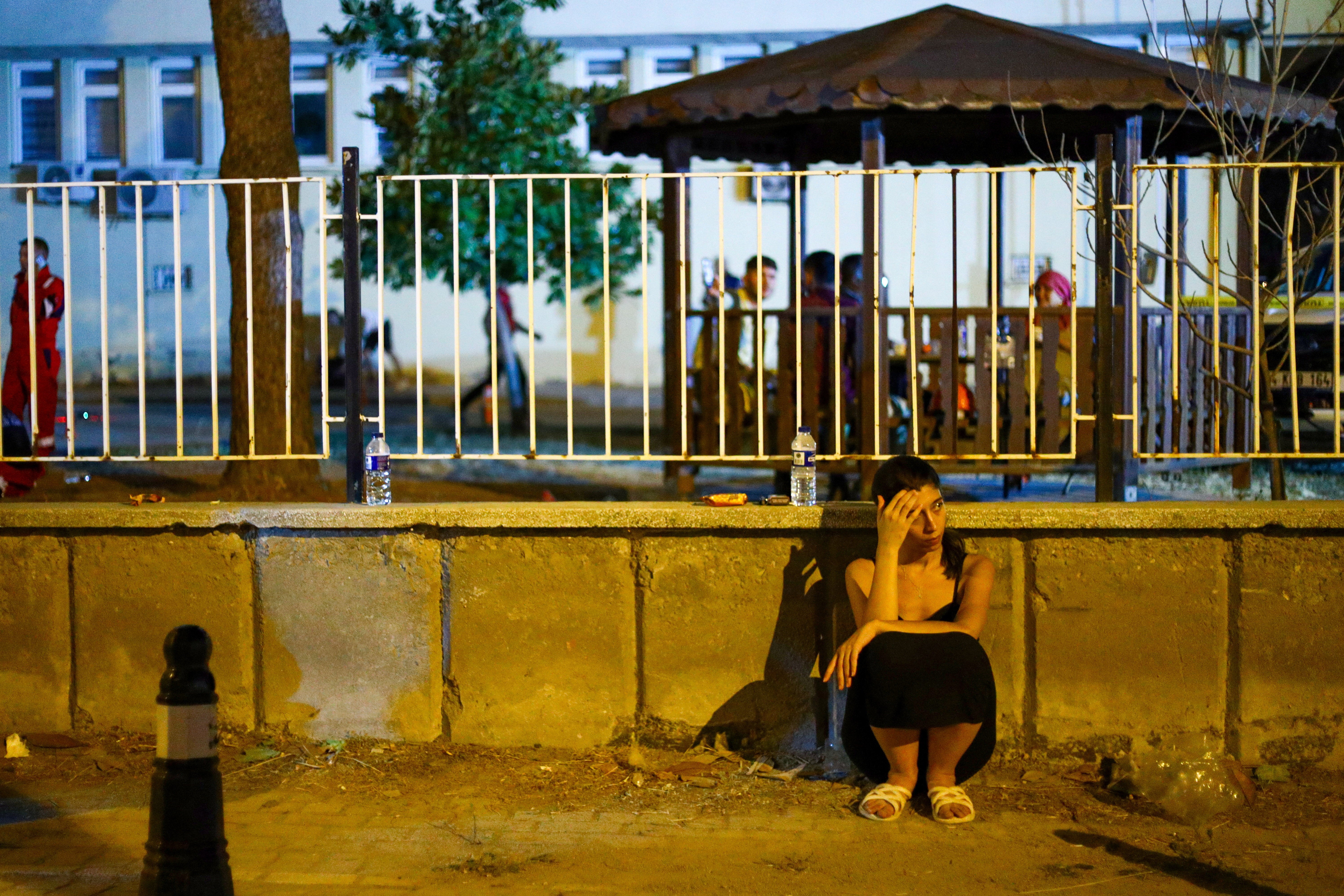A woman sits near the site of a collapsed building following an earthquake in Sindirgi