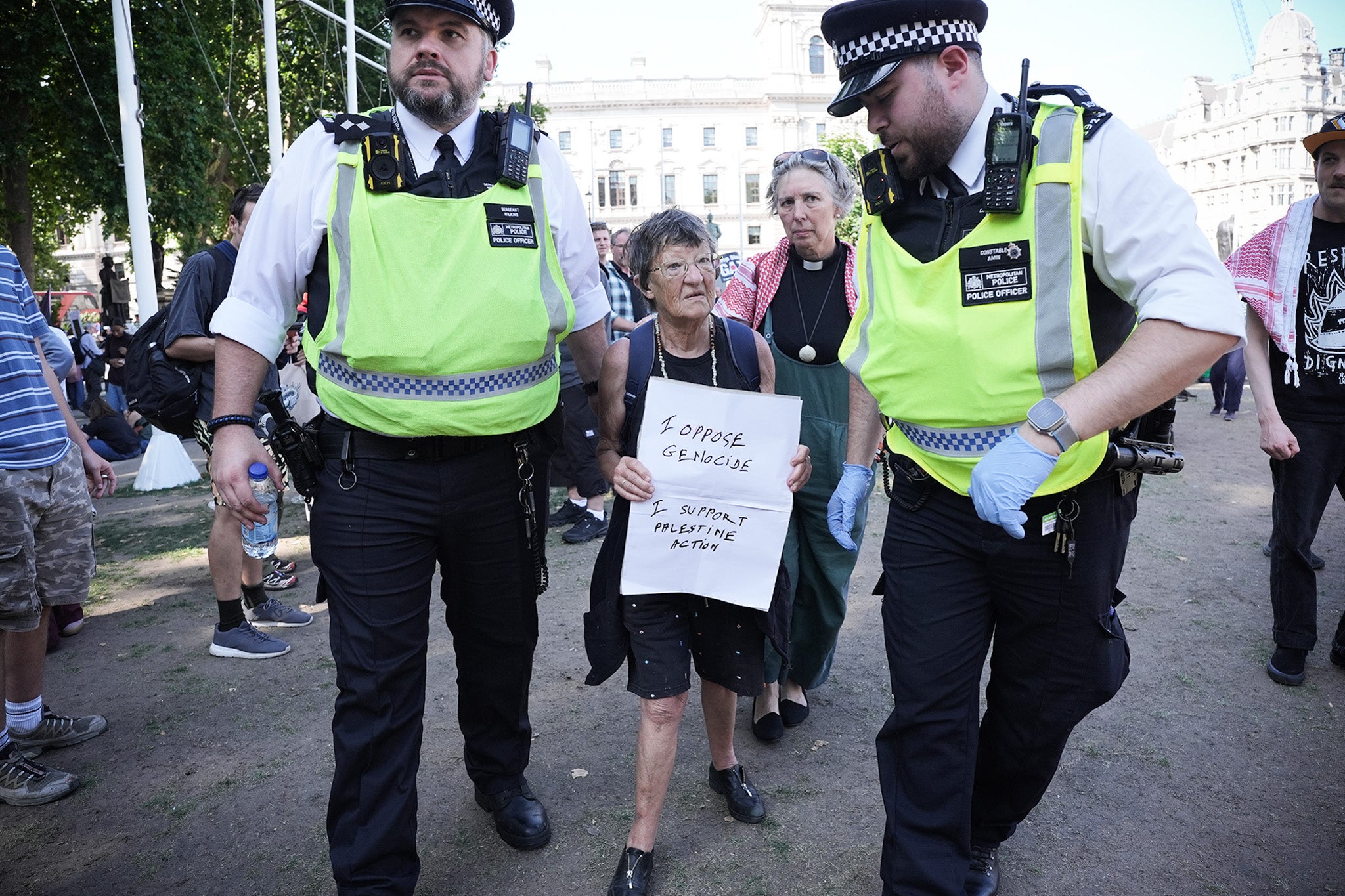 A women holding a sign in support of Palestine Action is detained by police outside Parliament Square on Saturday