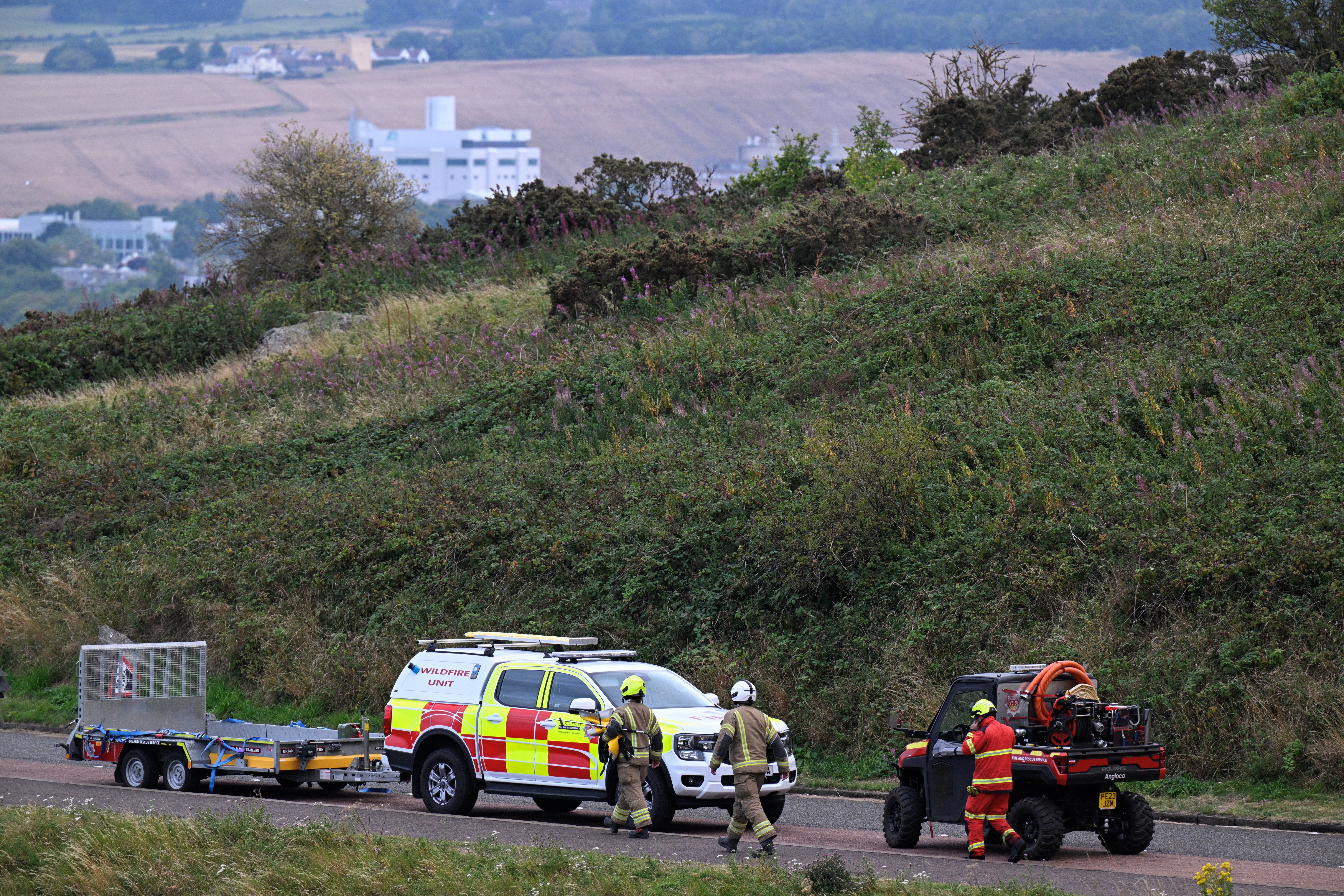 Firefighters work at the scene of a wildfire at Arthur's Seat