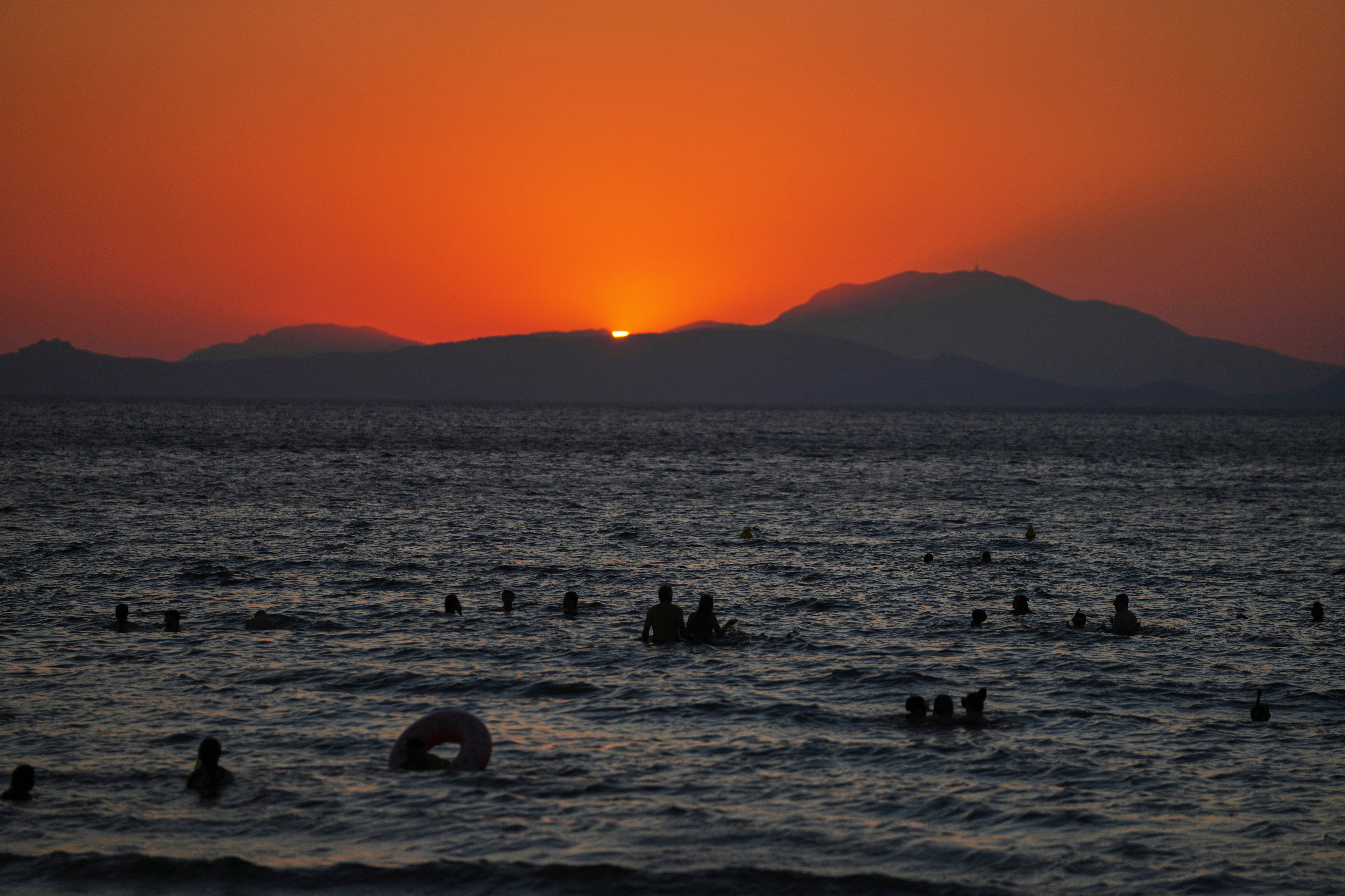 People enjoy the sea as the sun sets during a warm and windy day at Kavouri beach in southern Athens, Greece, Monday, Aug. 11, 2025. (AP Photo/Thanassis Stavrakis)