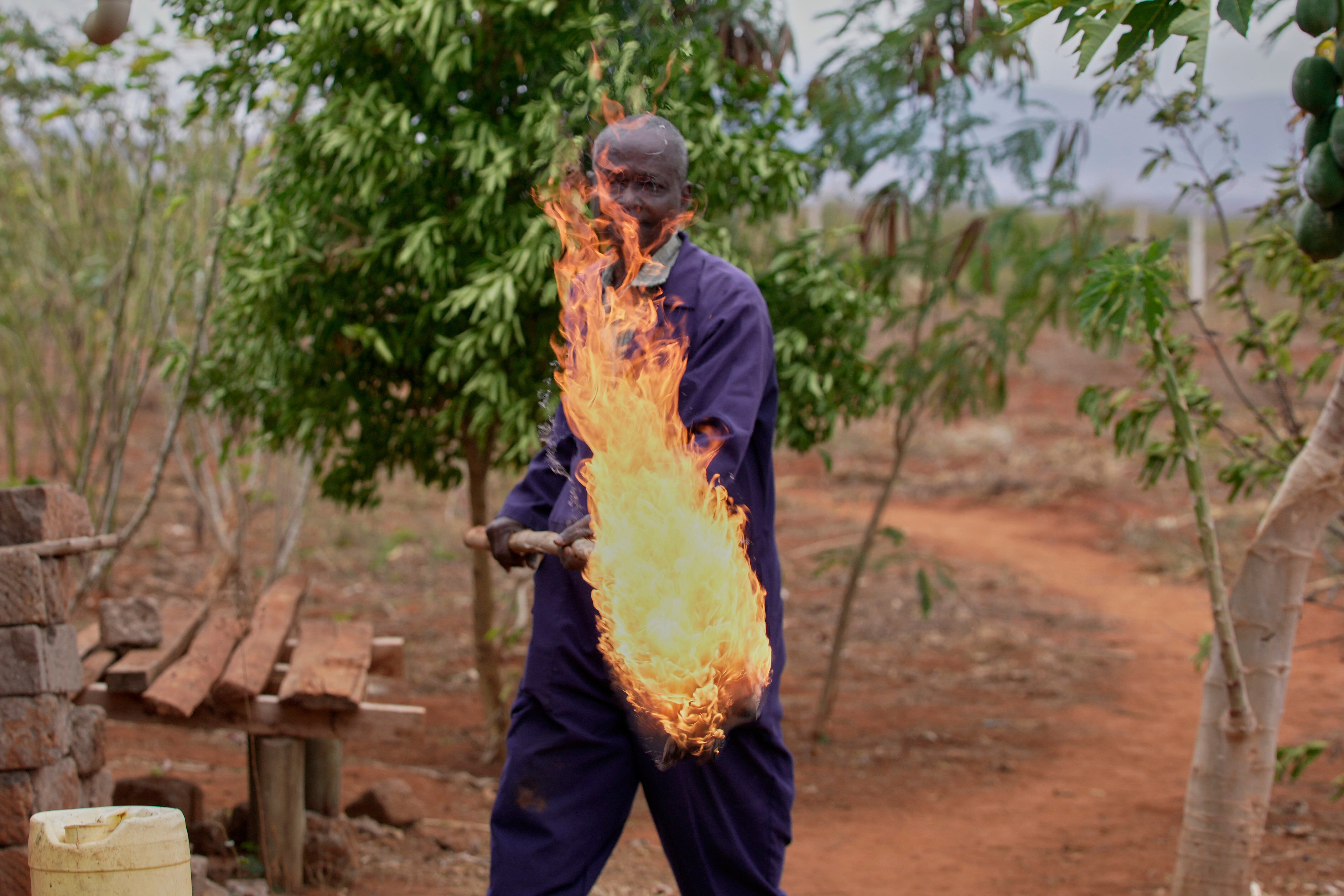 Richard Shika demonstrates how he uses fire to scare away elephants around his farm in Voi town, Taita-Taveta County, Kenya