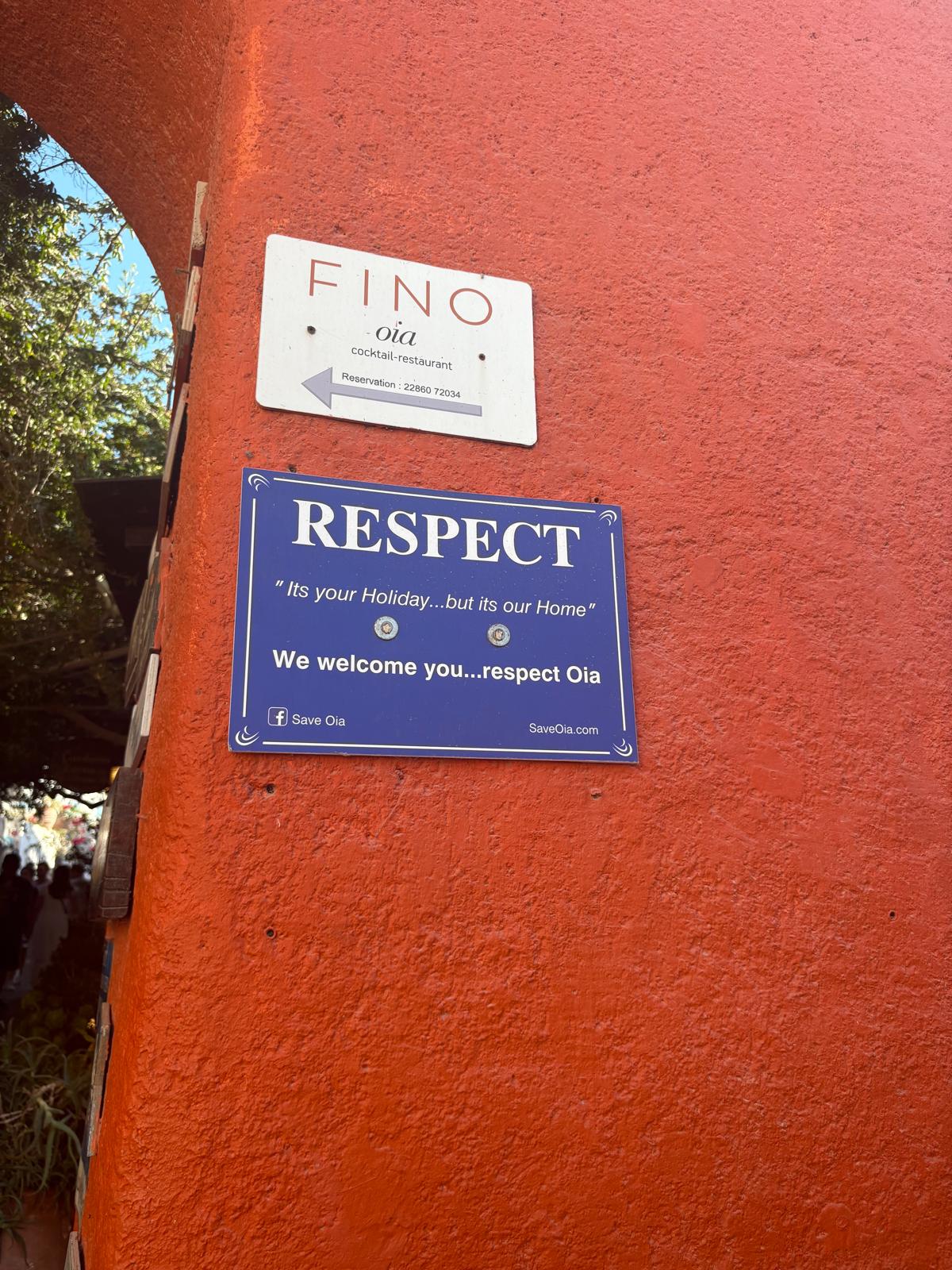 A sign asking visitors to respect the town of Oia