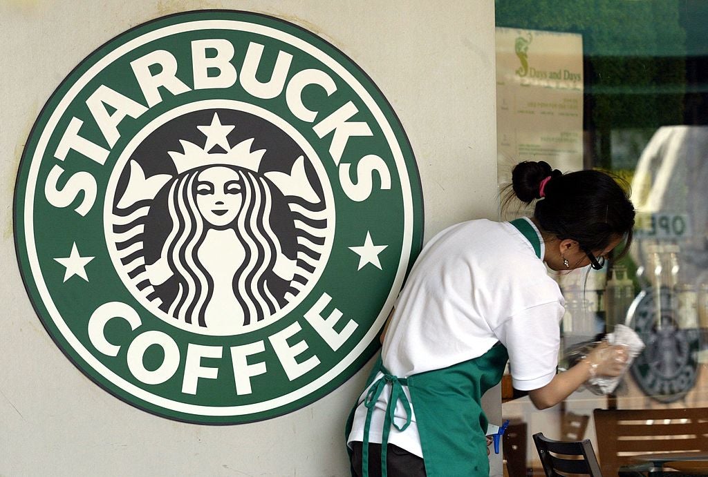 A Starbucks worker cleans the window next to a company logo at a coffee store on 31 May, 2006 in Seoul, South Korea