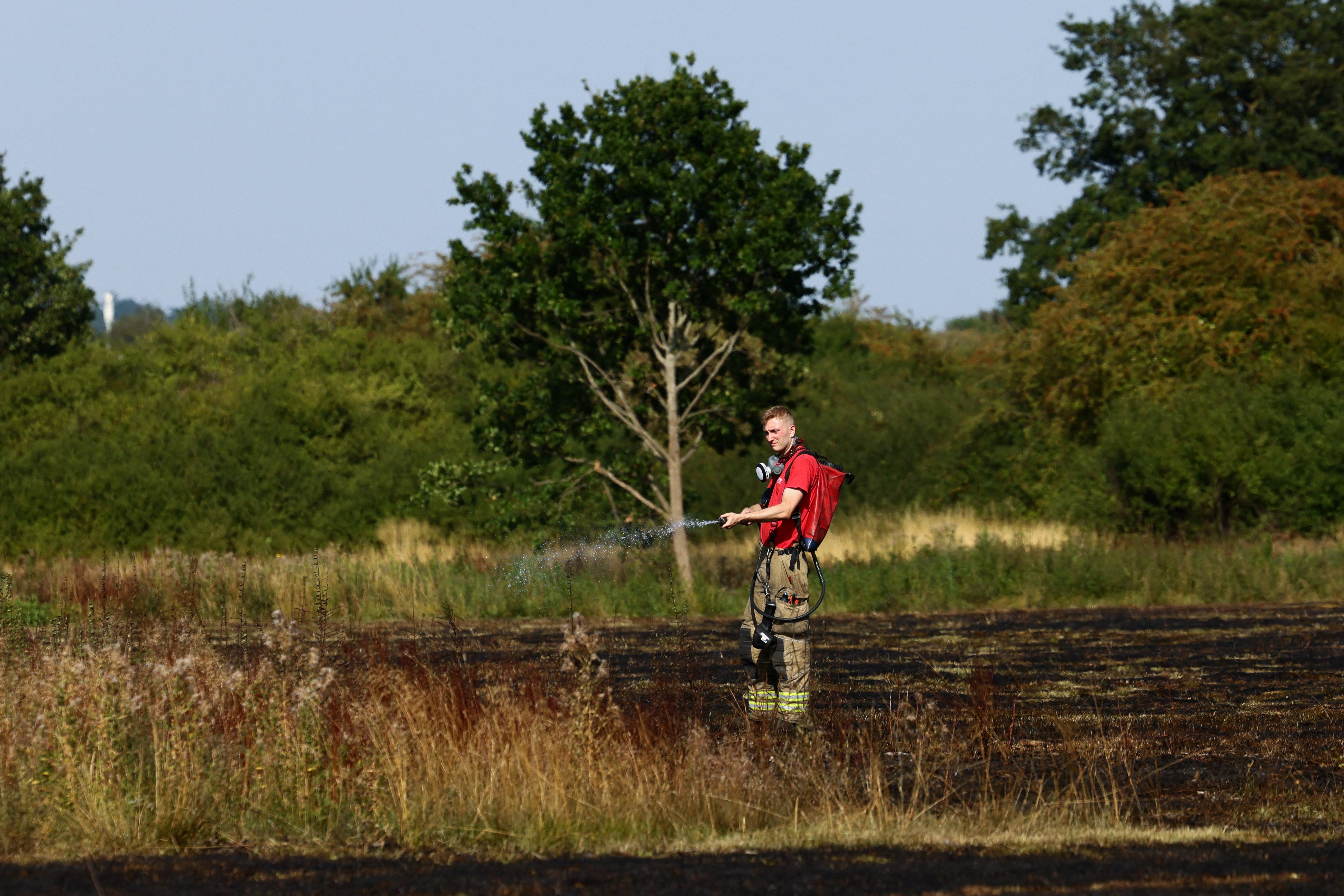 A firefighter works at the scene of a wildfire in Northolt, north-west of London, amid the heatwave on Tuesday