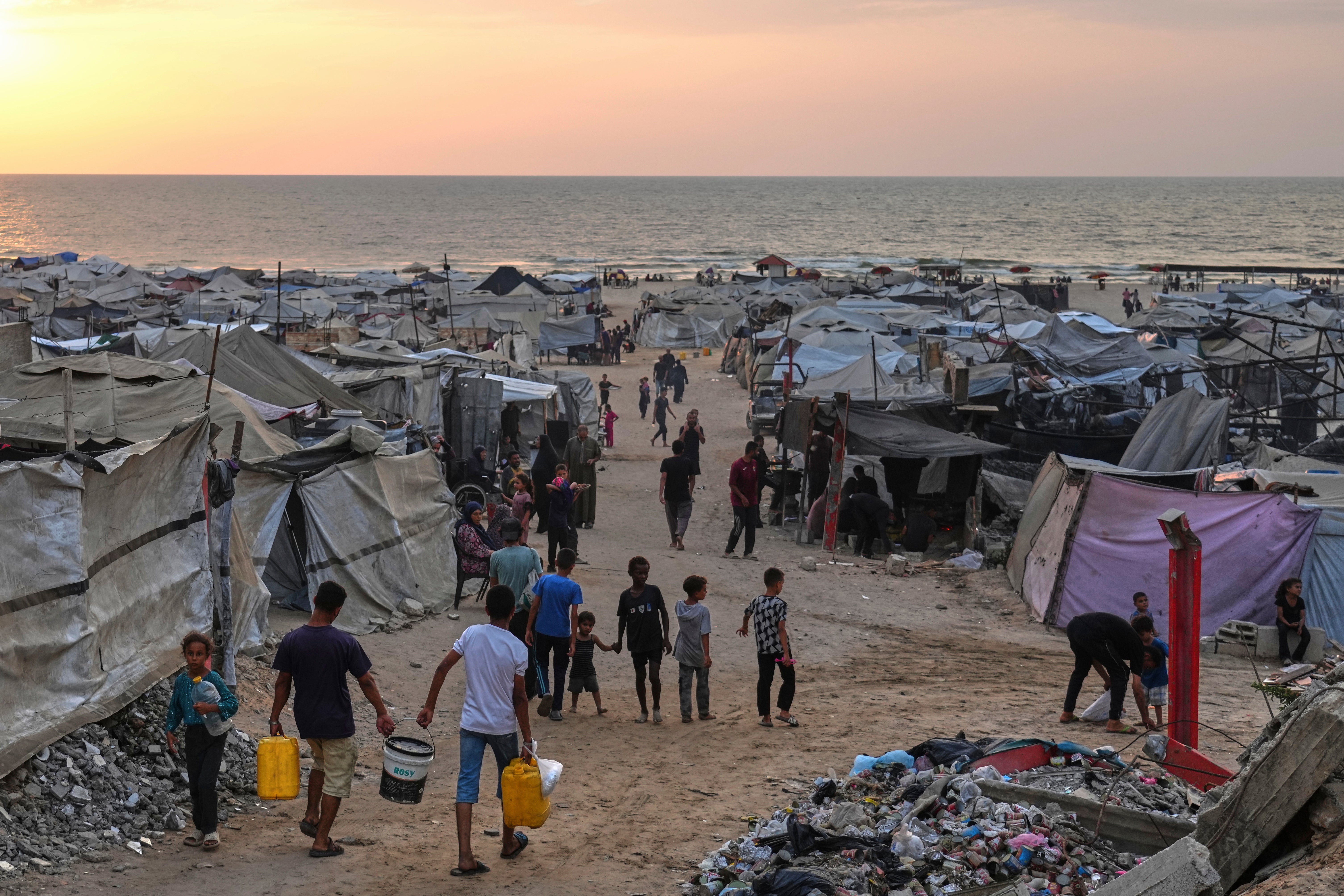 Displaced Palestinians walk through a makeshift camp along the beach in Gaza City