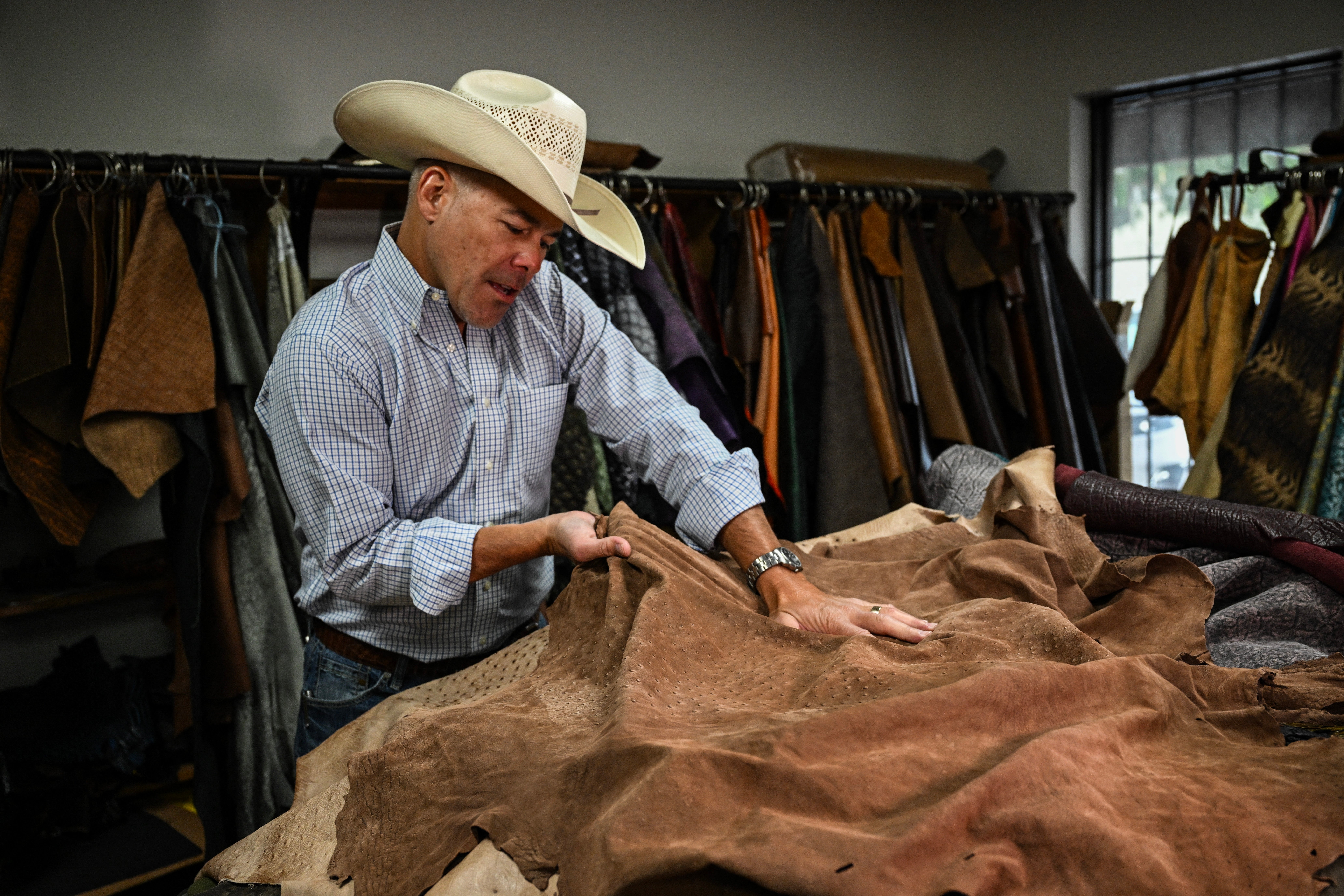 A cowboy boot maker in Mercedes, Texas tests a sheet of ostrich leather in July 2025