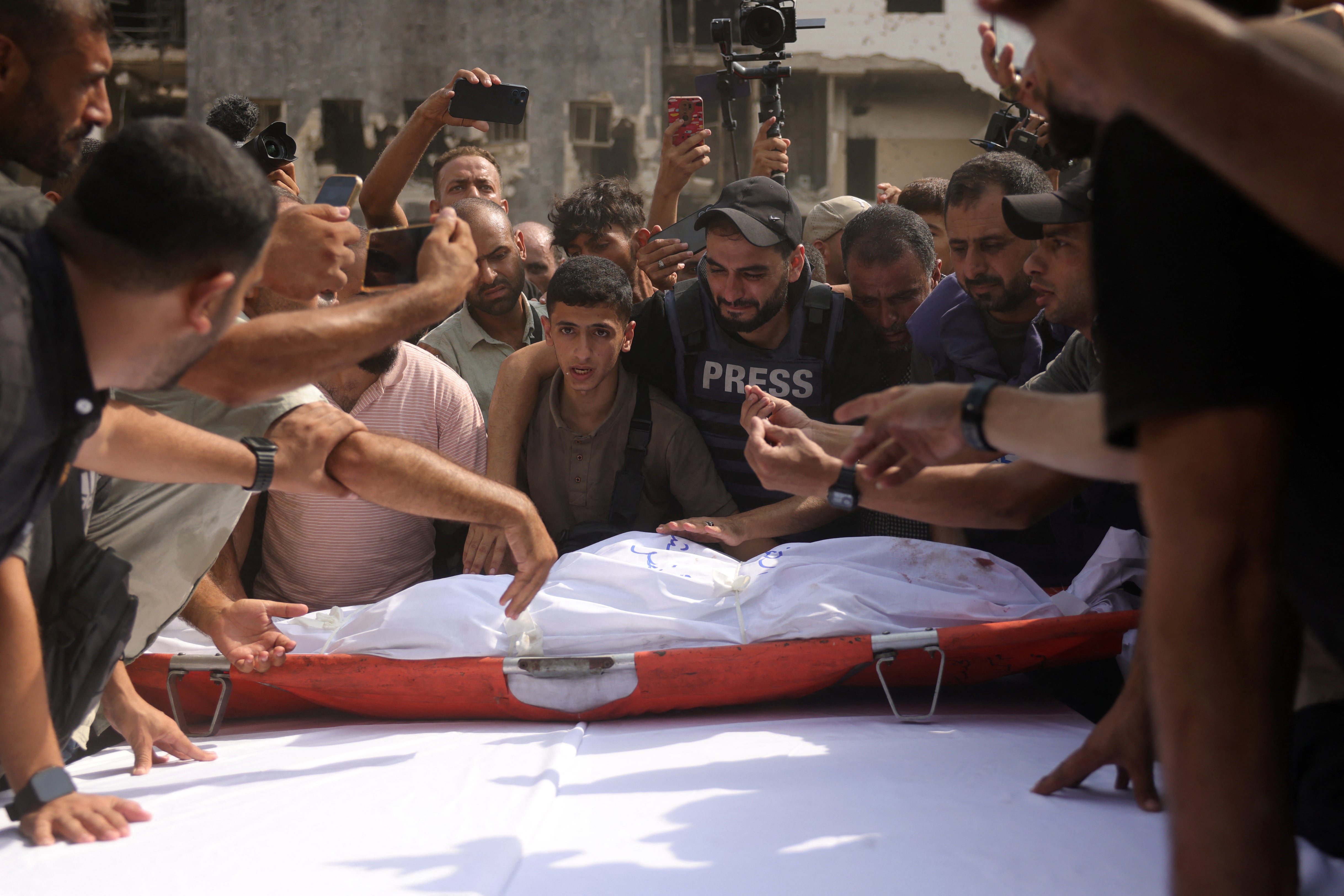 Mourners place the body of Al Jazeera correspondent Anas al-Sharif on a table ahead of a funeral procession in Gaza City