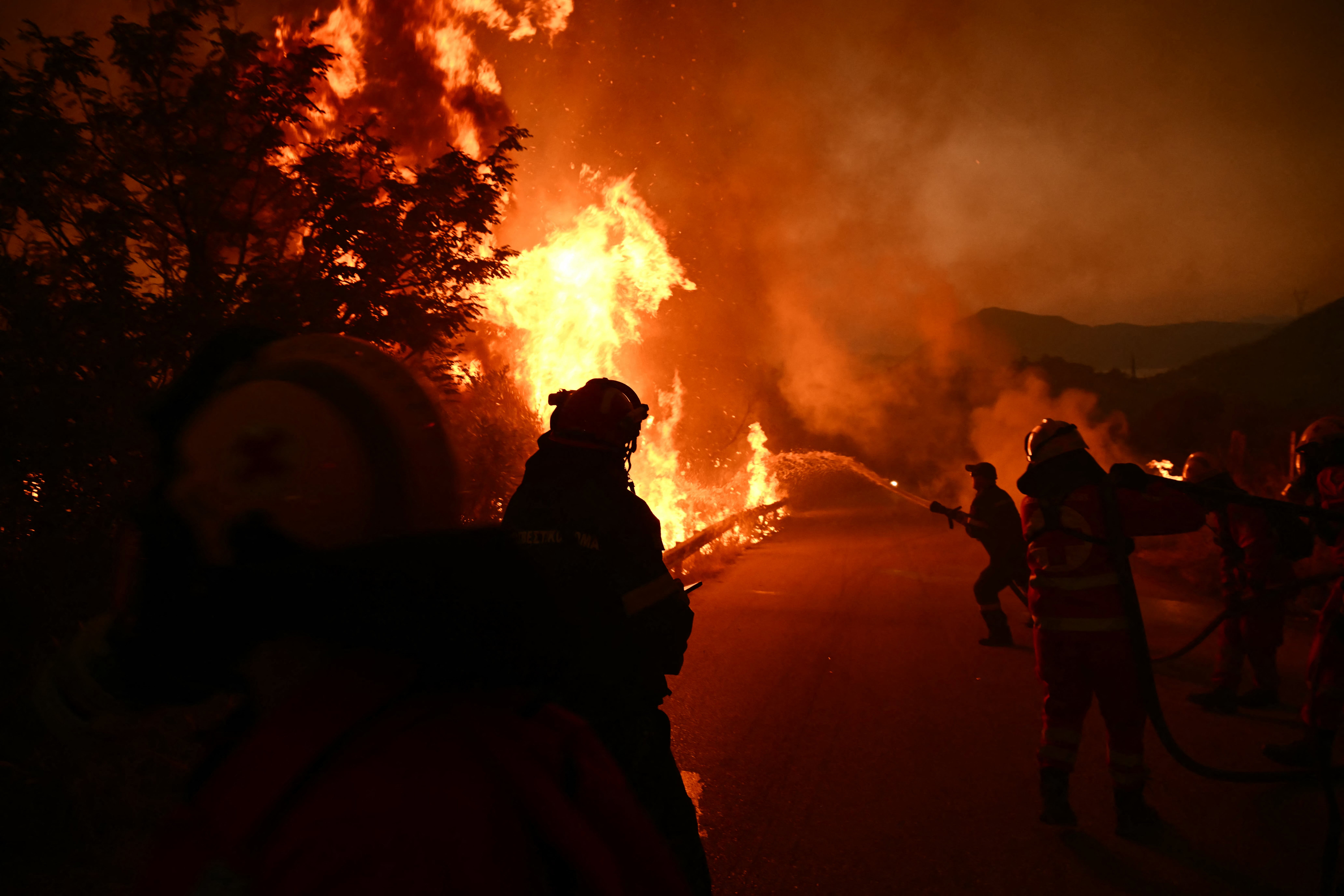 Firefighters work to extinguish a wildfire near the city of Patras, western Greece on August 13, 2025. Greece on August 13, 2025 battled to contain more than 20 wildfires including one menacing its third-largest city Patras as a heatwave stoked blazes and forced the evacuation of thousands in southern Europe