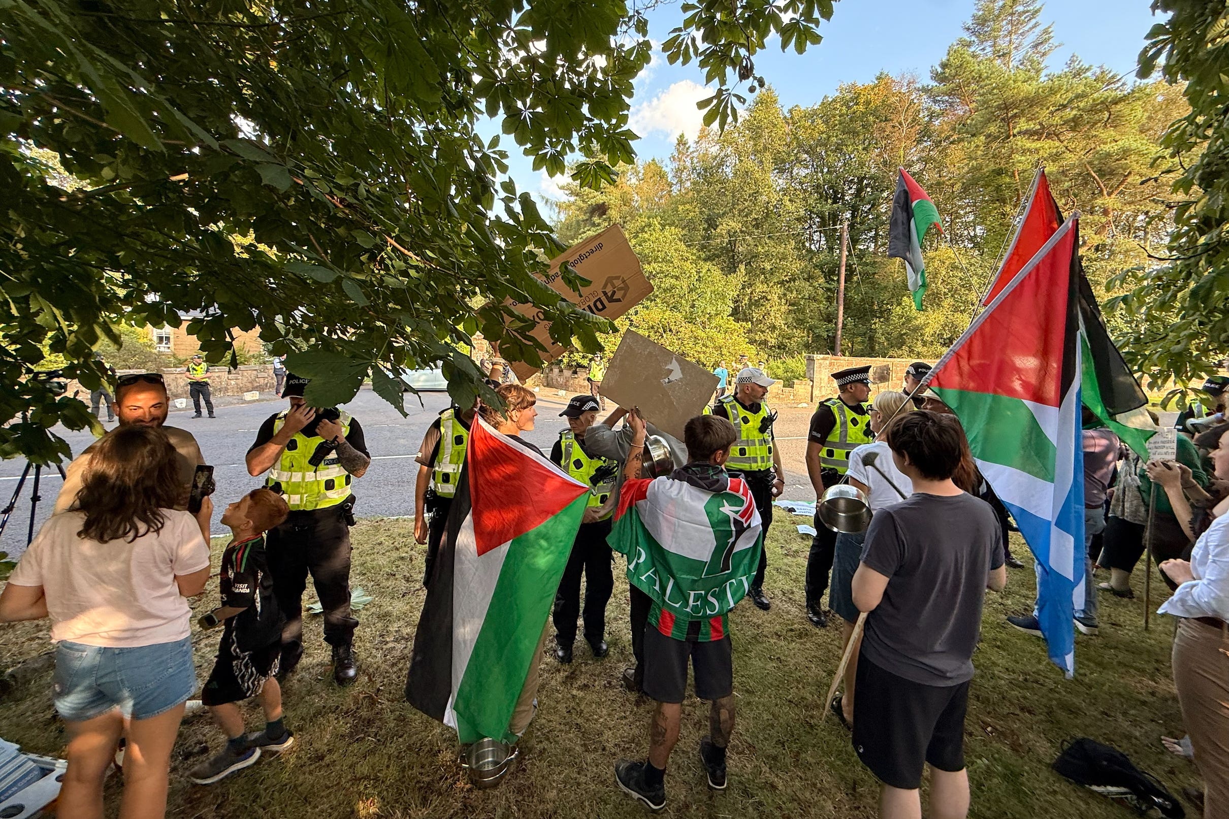 Police officers speak to protesters, some holding Palestinian flags, outside the Carnell Estate in Ayrshire (Craig Meighan/PA)