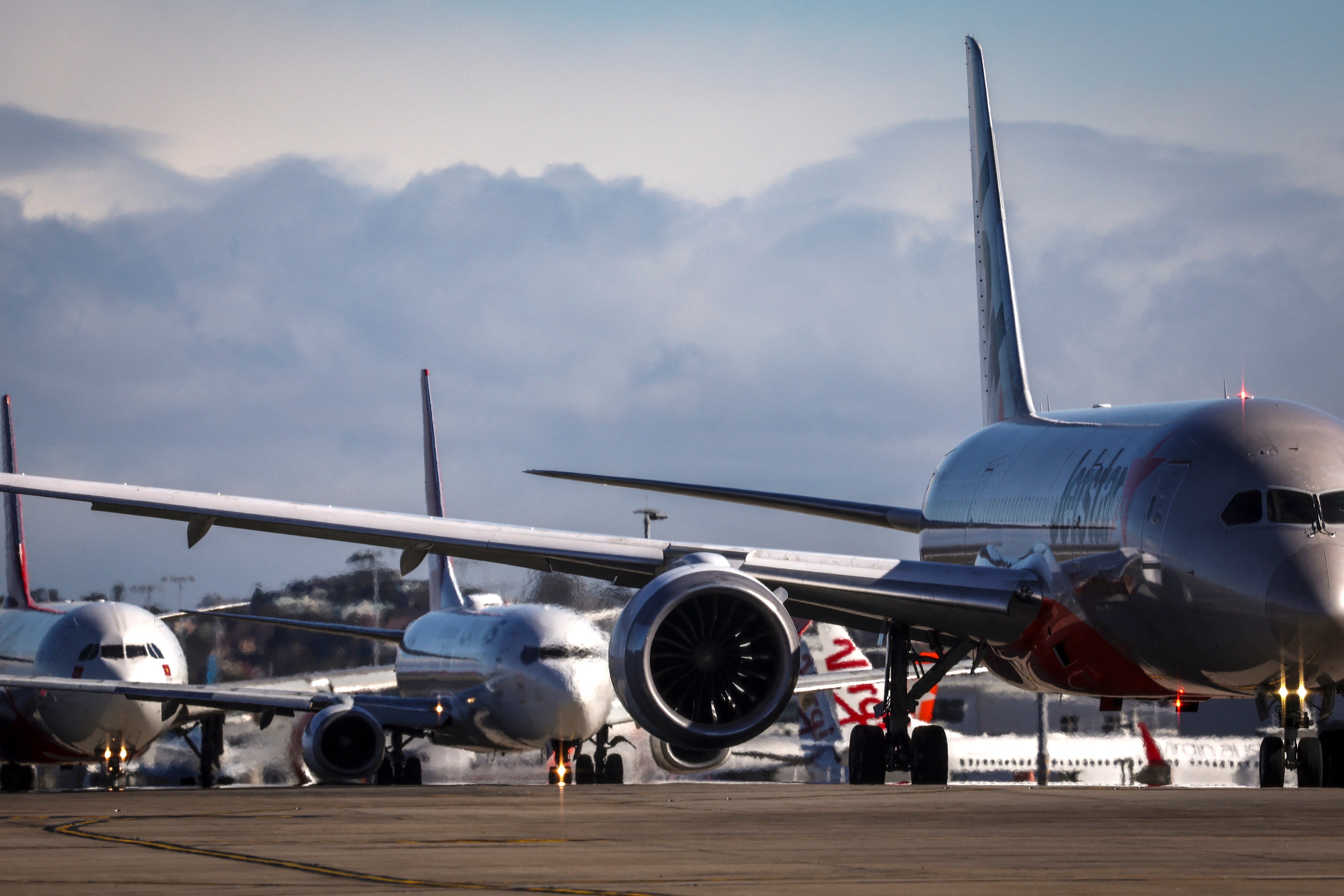 A Jetstar Boeing 787-8 plane (R) and a Qantas Boeing 737-800 plane (C) line up at Sydney International Airport