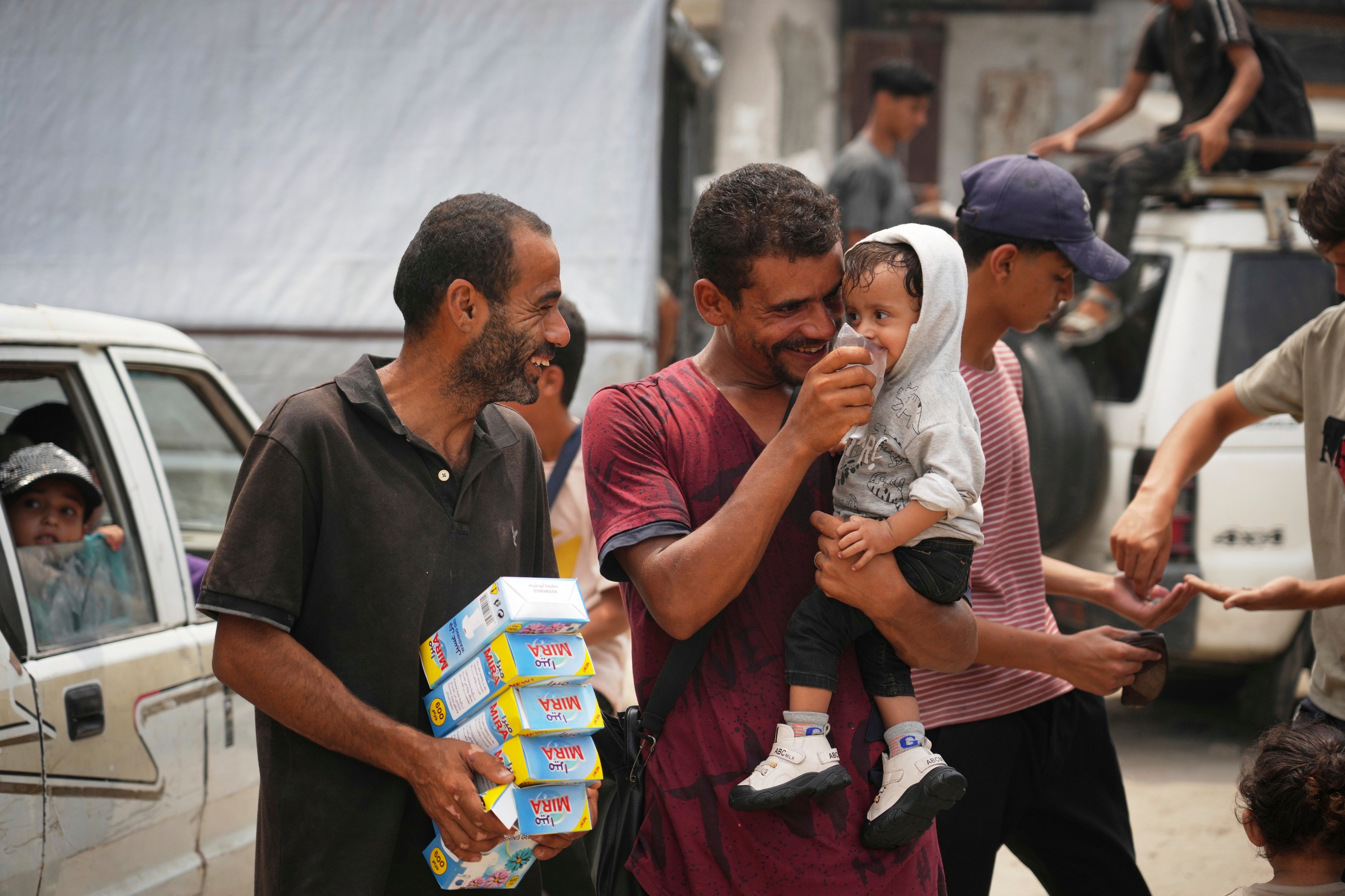 In the summer heat, a man gives a child water from a plastic bag he has just bought for one shekel, in Gaza City, 12 August 2025.