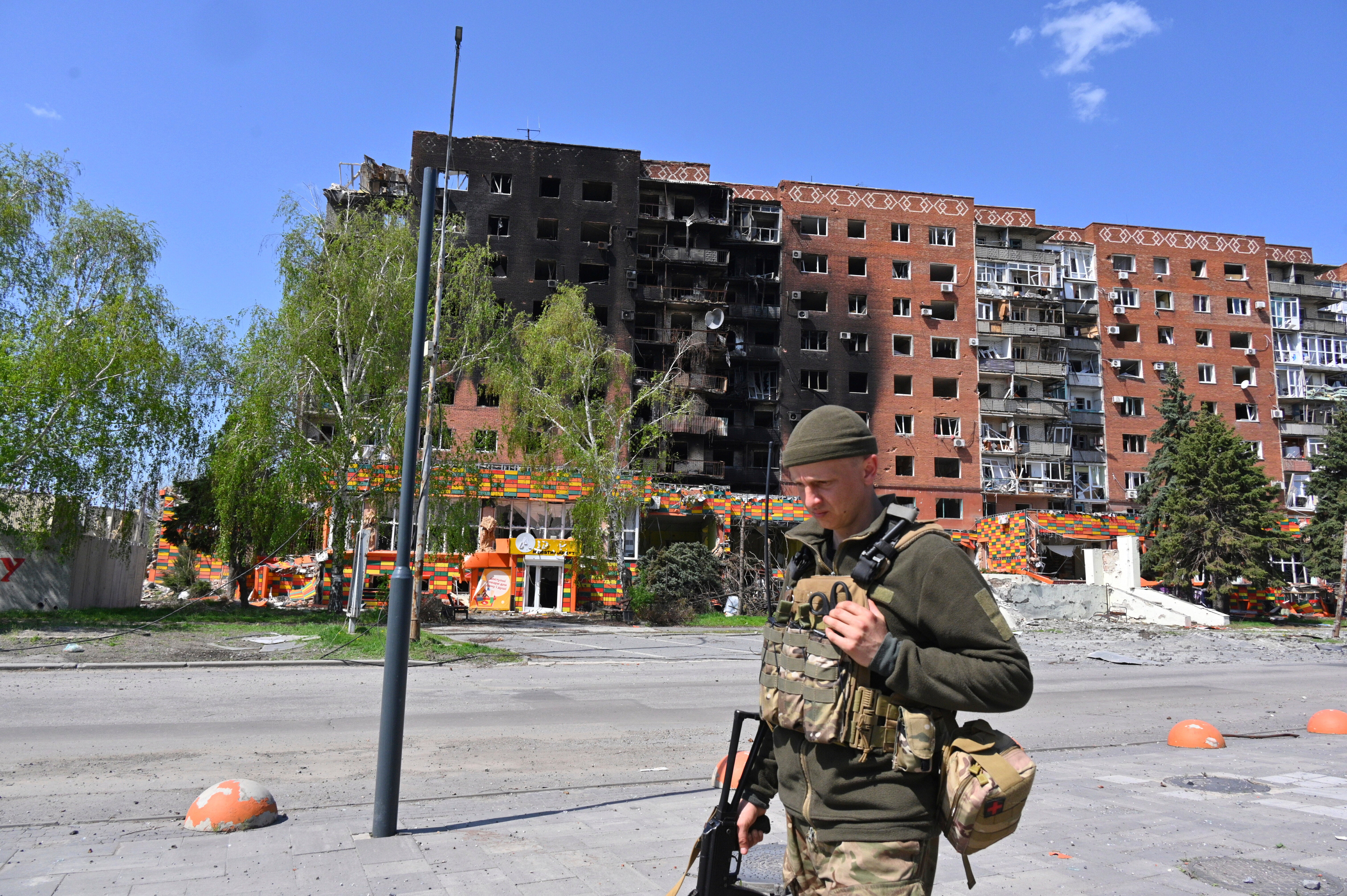 A Ukrainian soldier walks past damaged buildings in central Pokrovsk