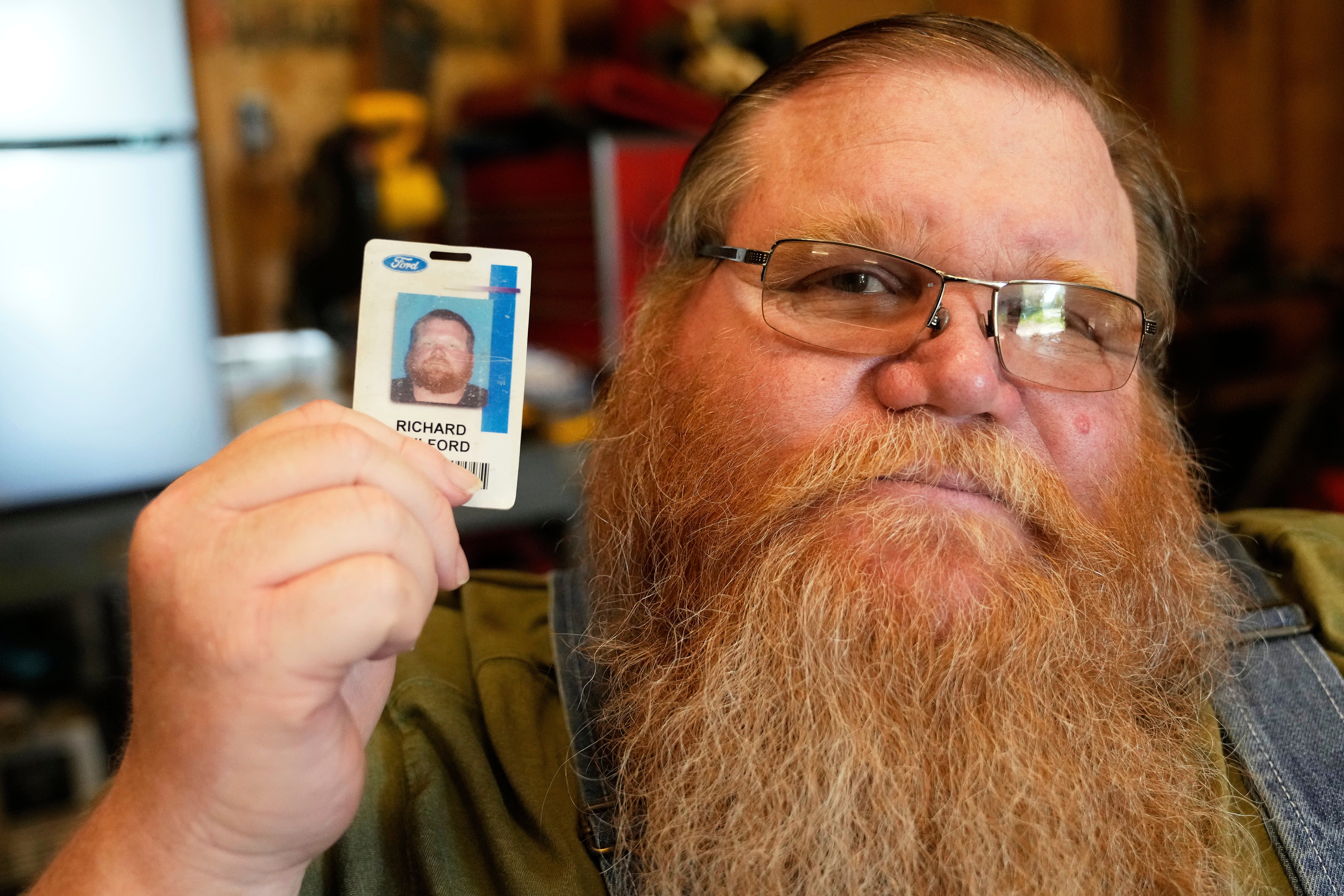 Richard Guilford poses for a portrait with an ID card from his recently recovered wallet that he lost 11 years ago
