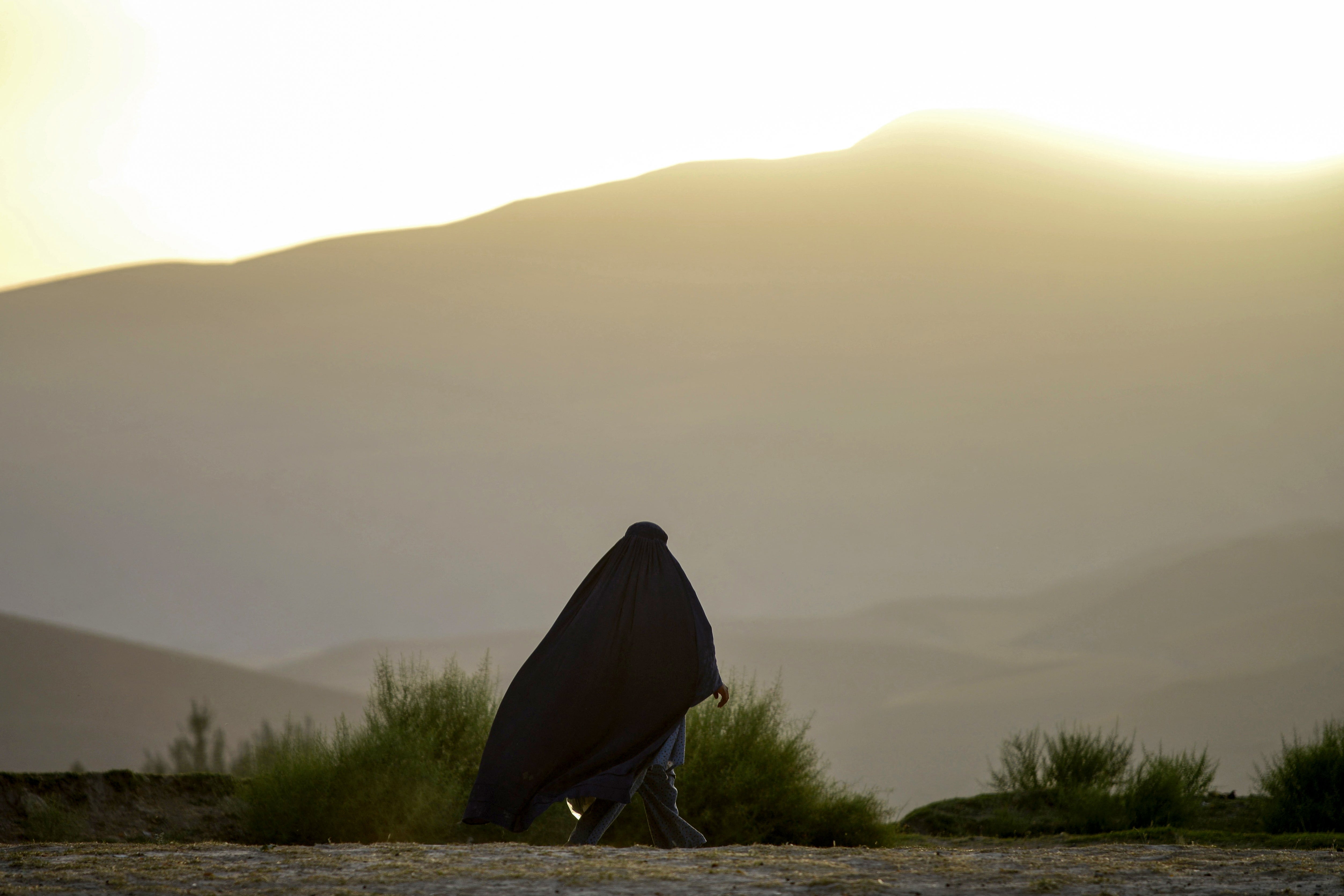 An Afghan burqa-clad woman walks along a road on the outskirts of Fayzabad district in Badakhshan