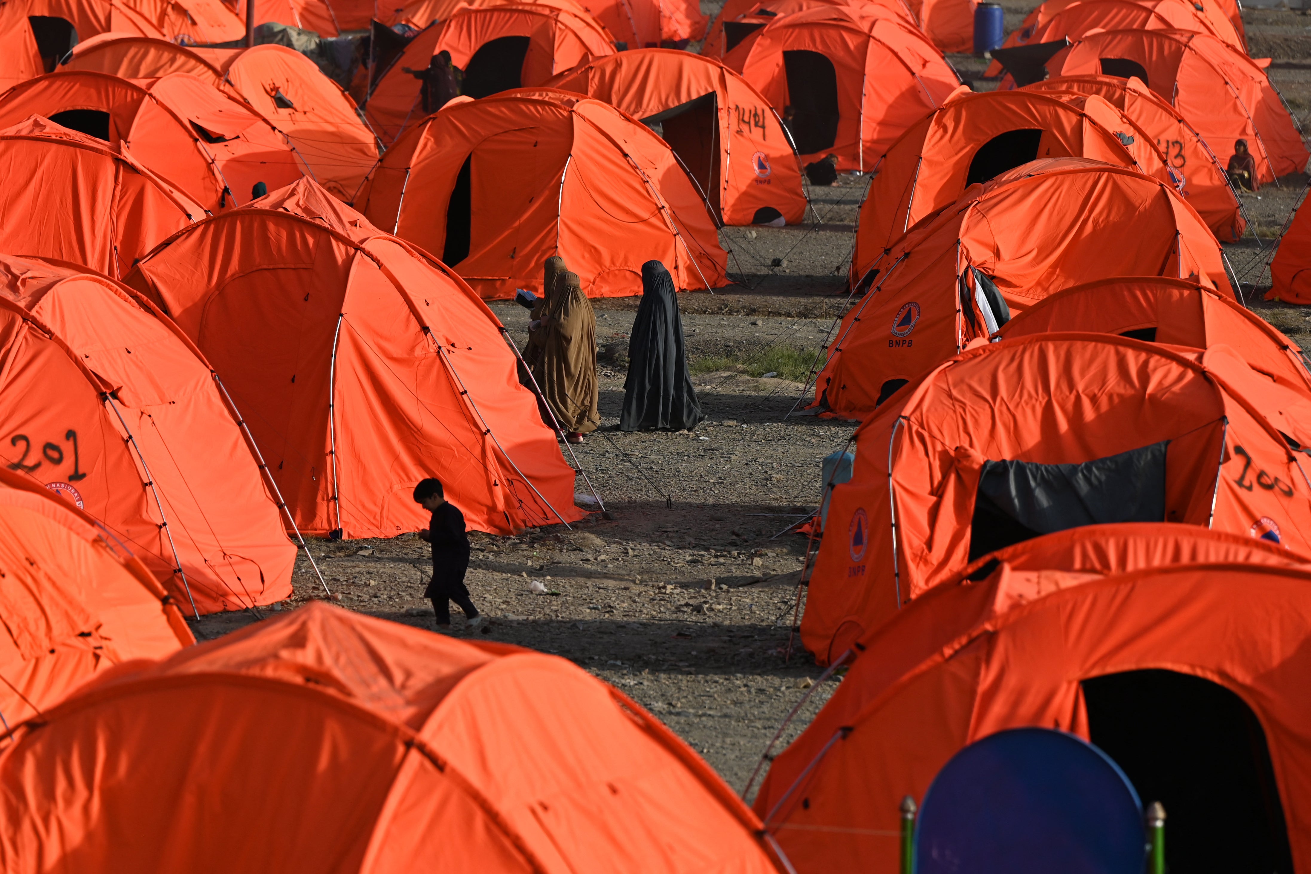 Afghan refugee women walk through tents after arriving from Pakistan at a makeshift camp in Nangarhar province in Afghanistan