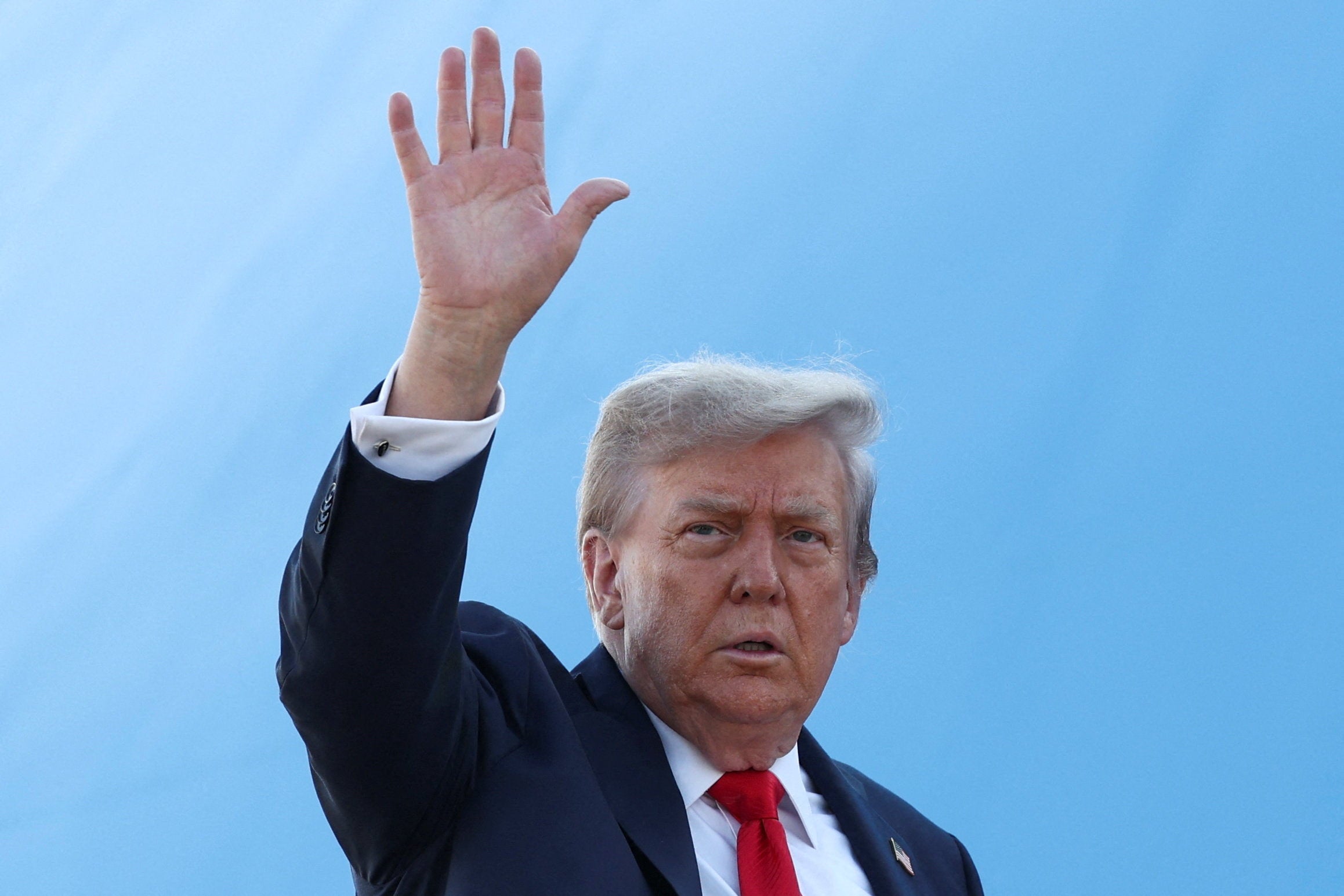 Trump waves to reporters as he boards Air Force One in the US