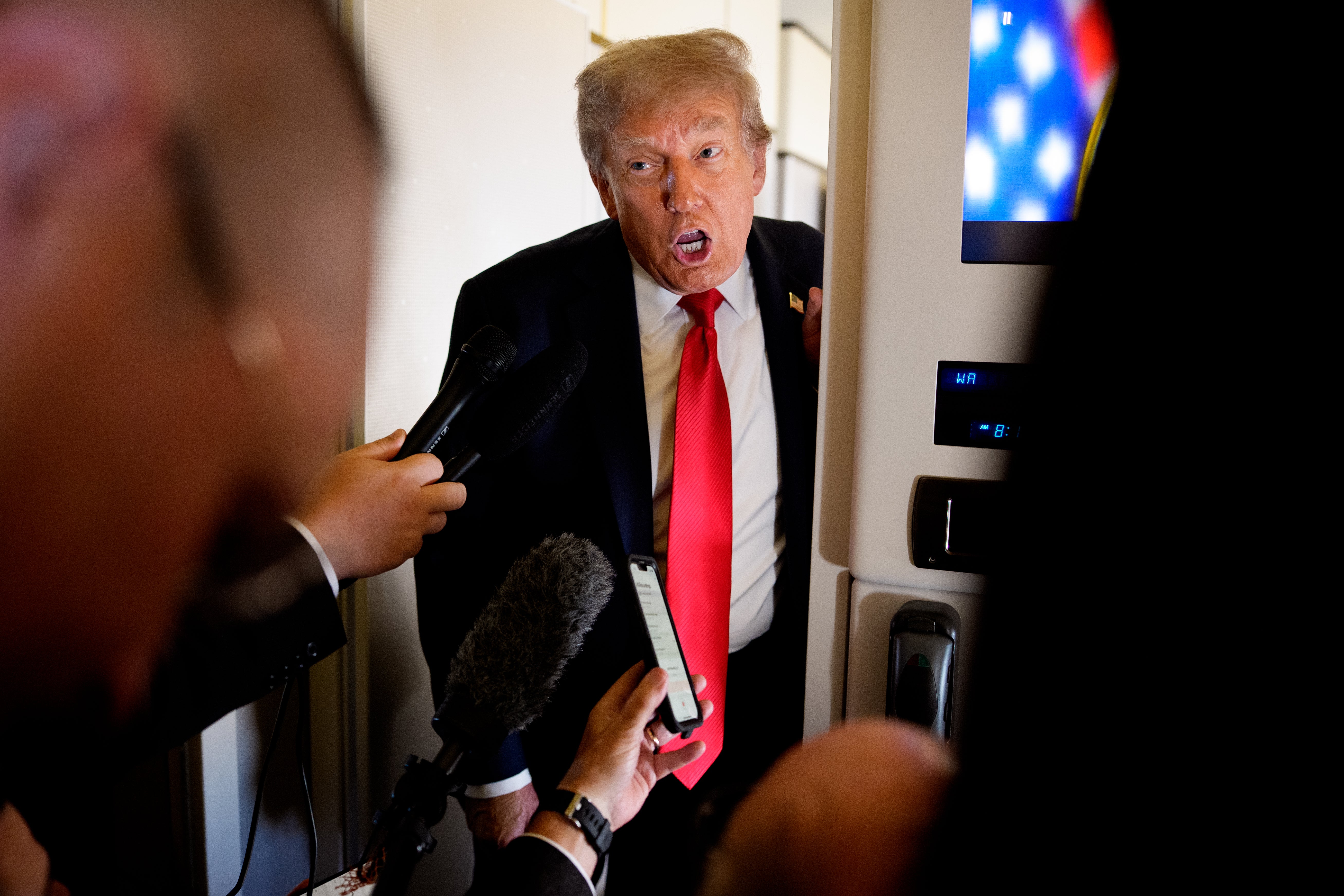 US President Donald Trump speaks to members of the media aboard Air Force One