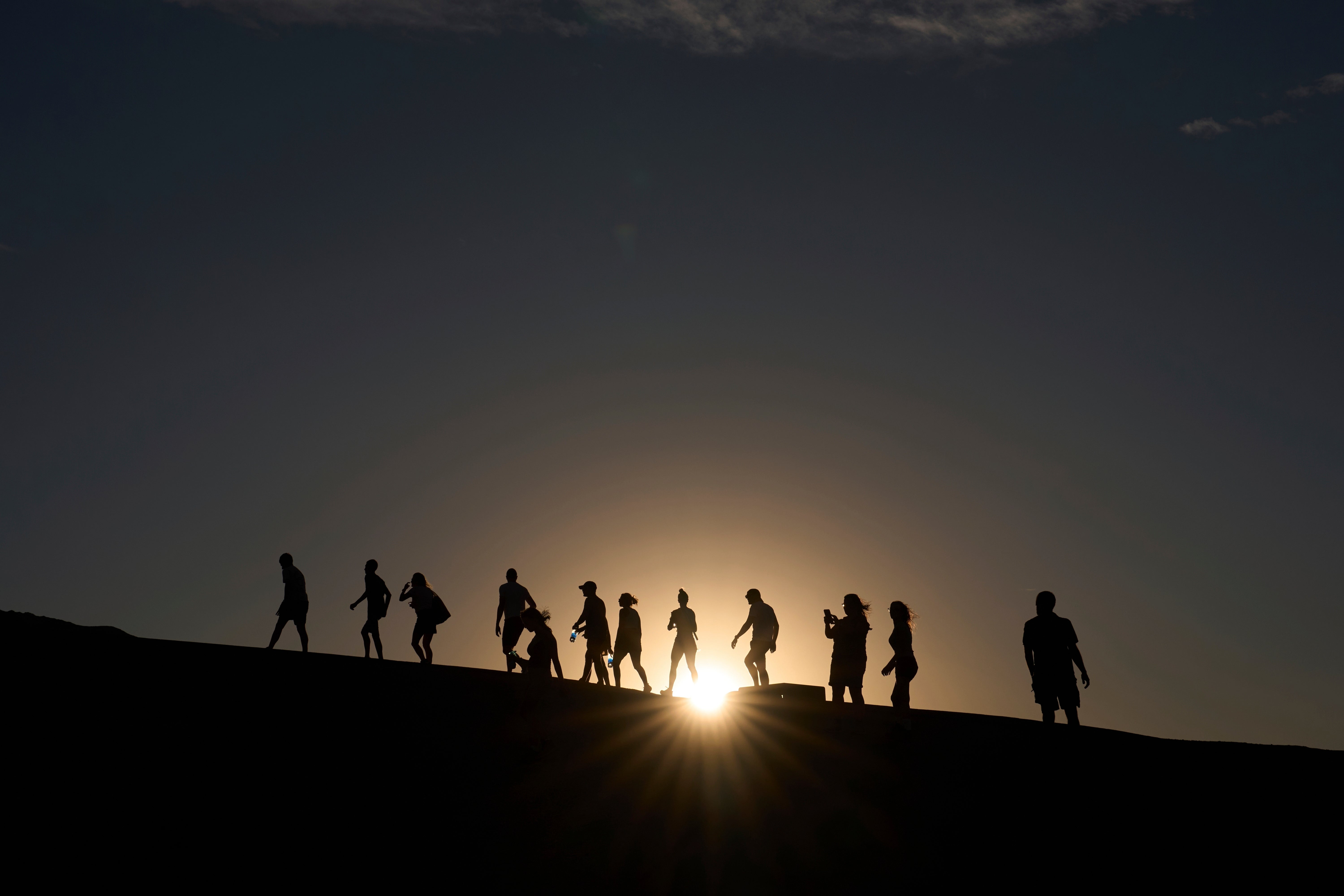 People walk up to an overlook at Zabriskie Point in Death Valley National Park, California