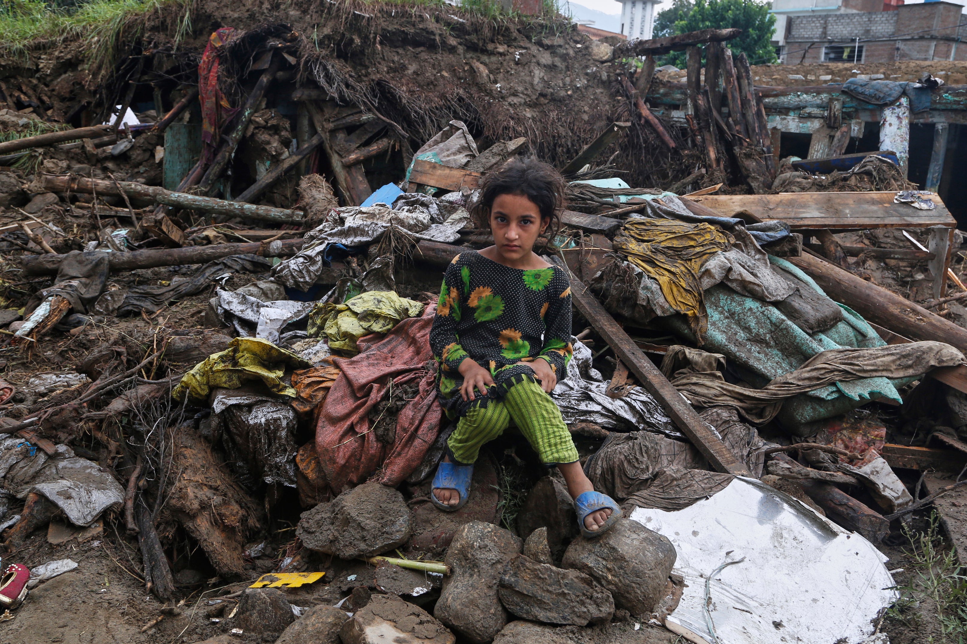 A girl sits amid the rubble of her damaged home following Friday's flash flooding at a neighbourhood of Pir Baba, an area of Buner district, in Pakistan's northwest