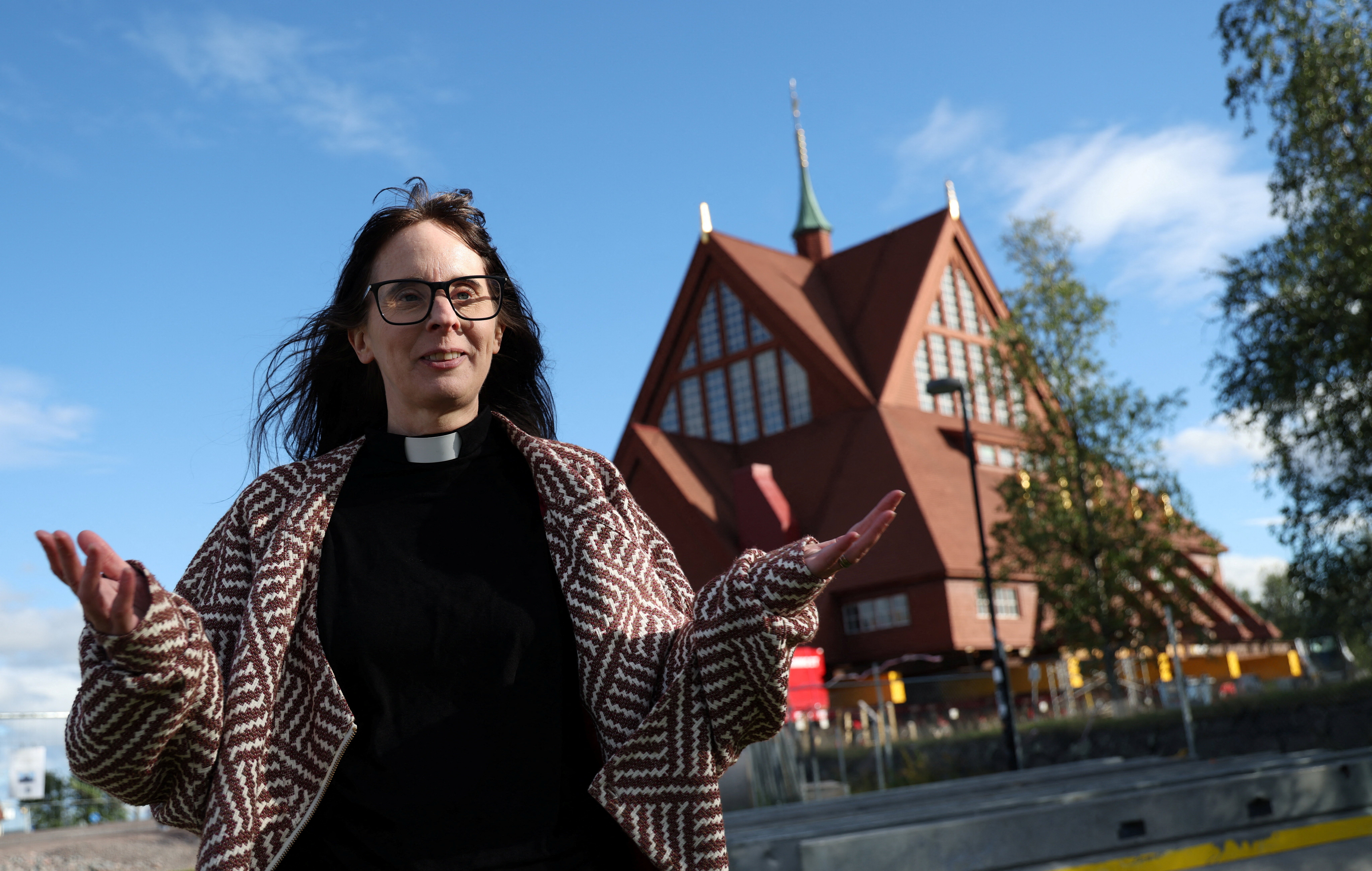 Pastor Lena Tjarnberg in front of the historic wooden church