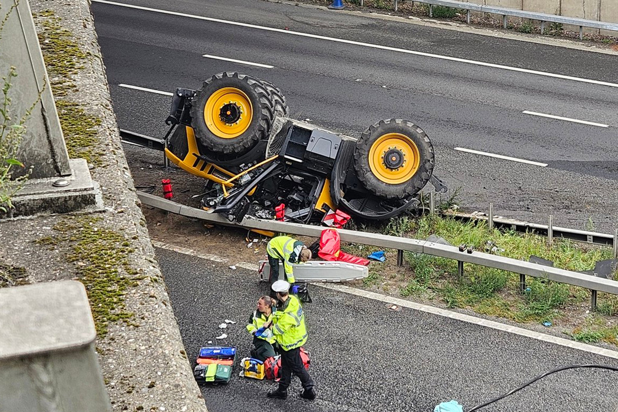 A major motorway has been closed in both directions after a tractor fell from an overbridge following a collision with a lorry