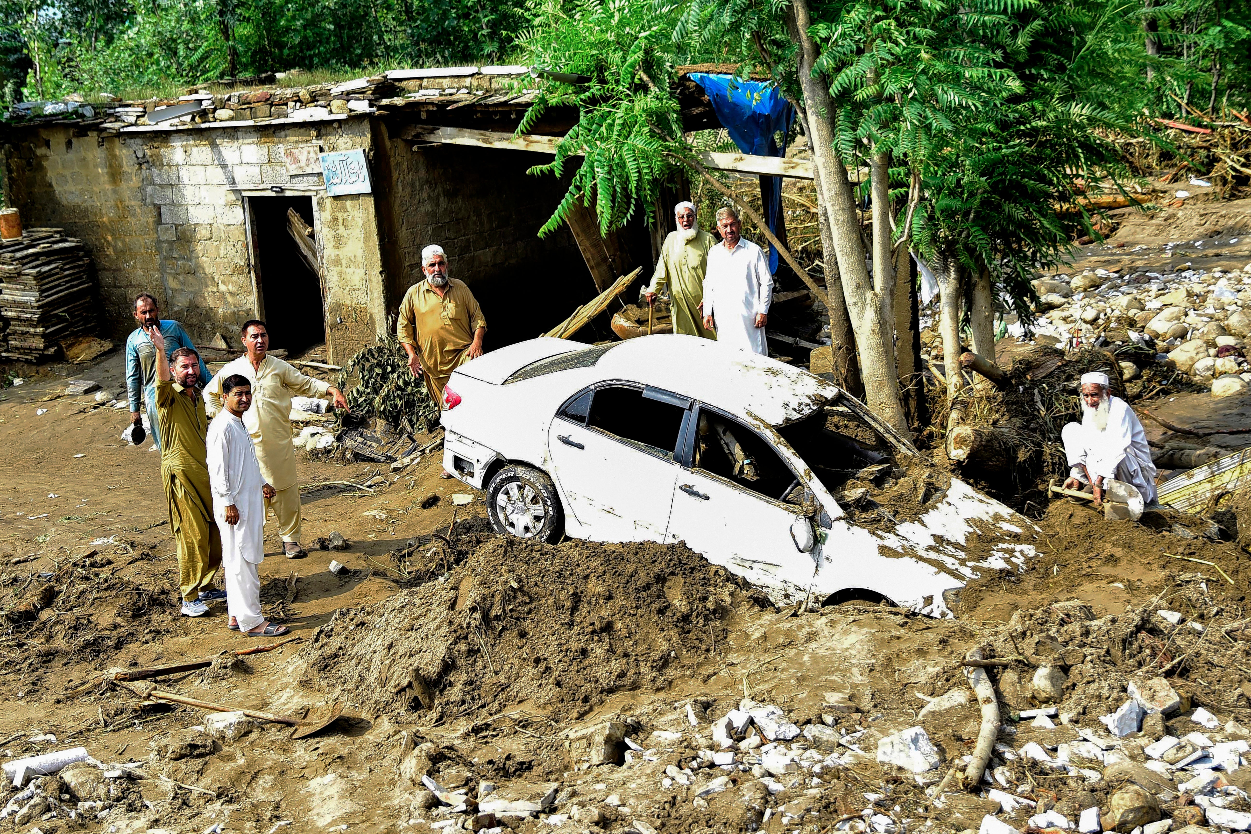 People struggle to retrieve a car from mud and debris after flash floods in the Buner district of Pakistan's mountainous Khyber Pakhtunkhwa province