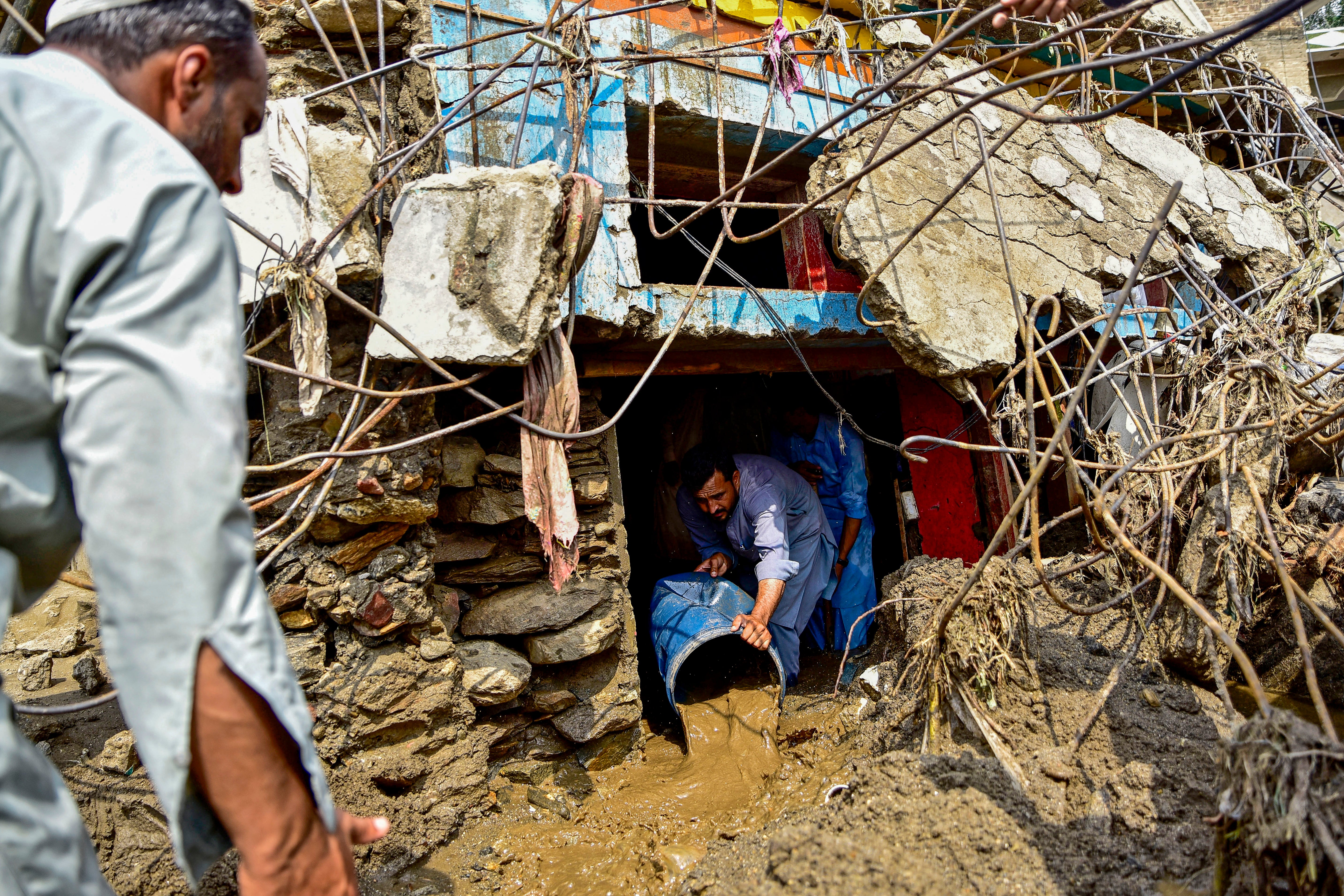 A resident removes sludge from his damaged house a day after flash floods in the Buner district of the monsoon-hit northern Pakistan's mountainous Khyber Pakhtunkhwa province on 16 August