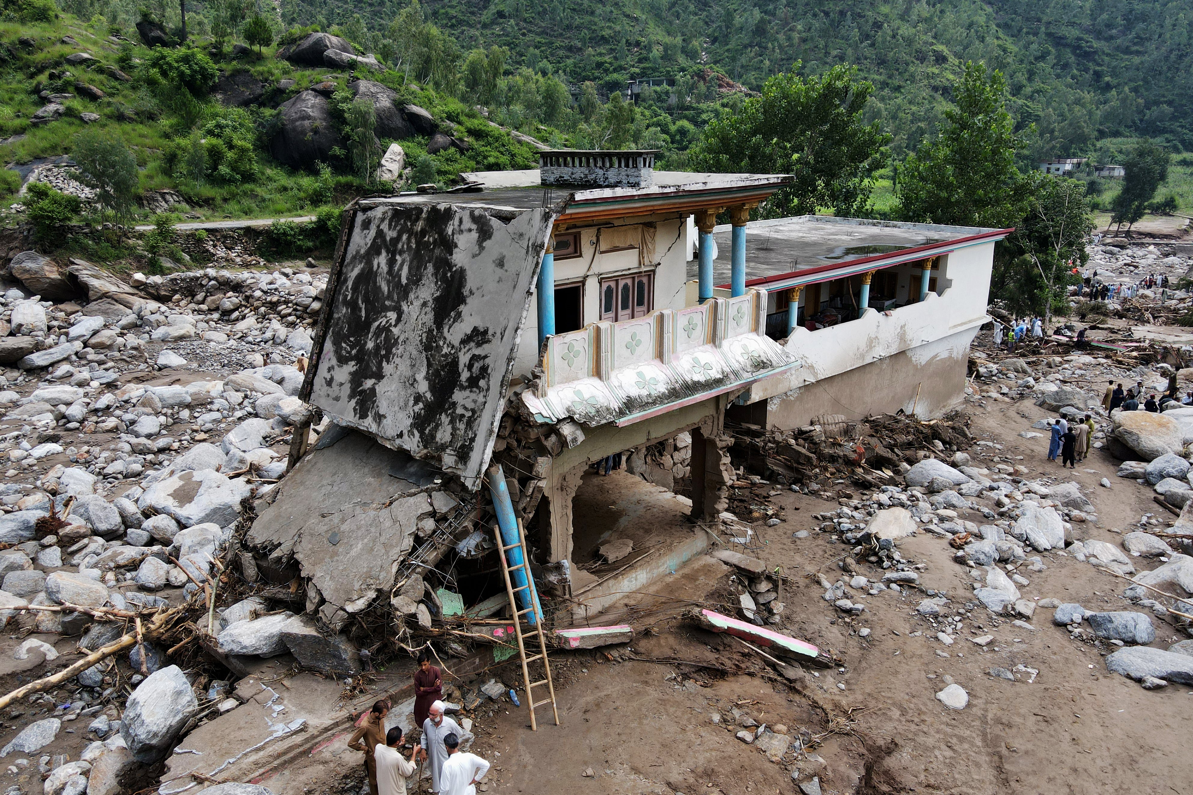 Flood survivors stand near a damaged house in Buner district of Khyber Pakhtunkhwa province