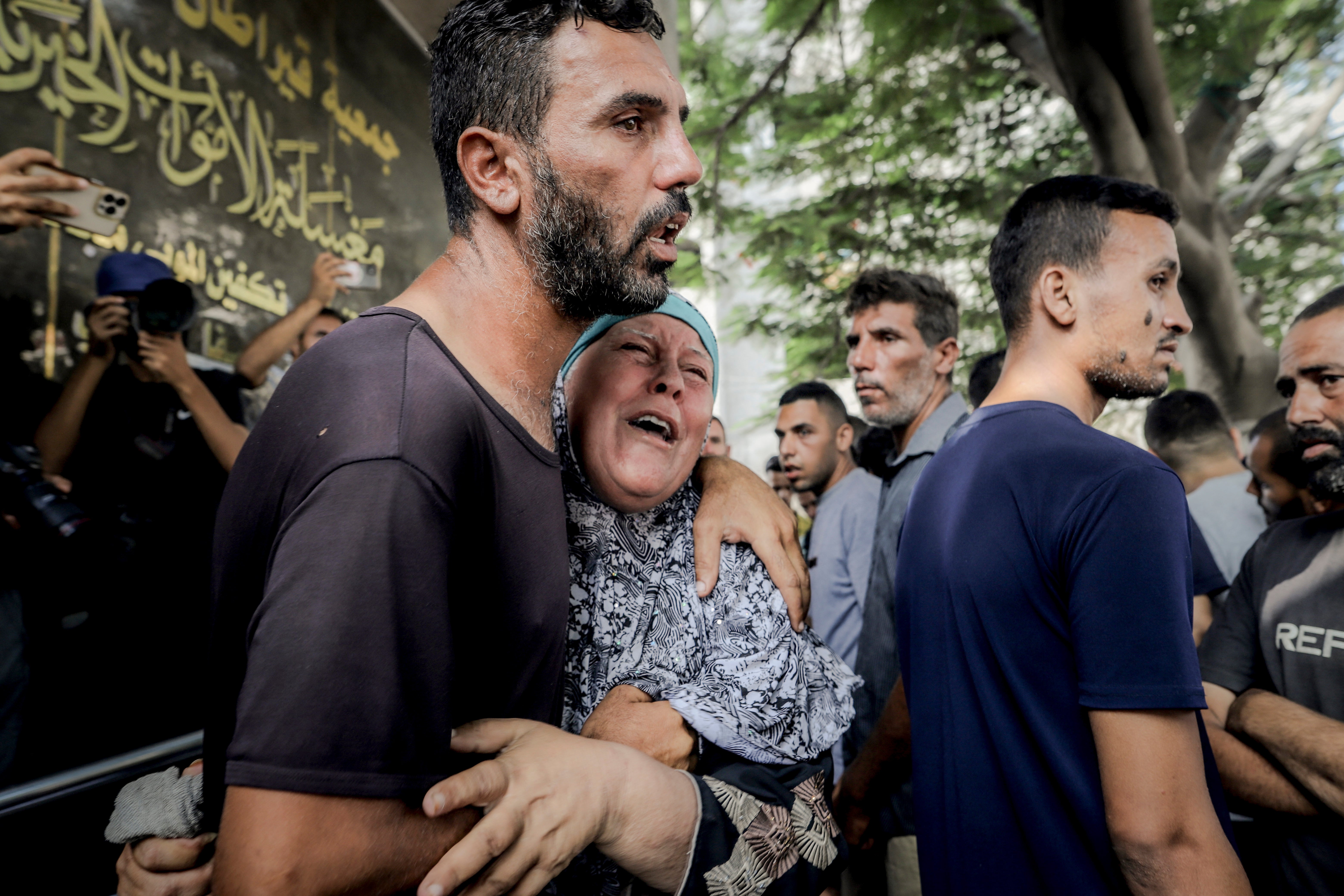 A woman weeps as she is embraced by a man at a funeral in Gaza City on 16 August 2025