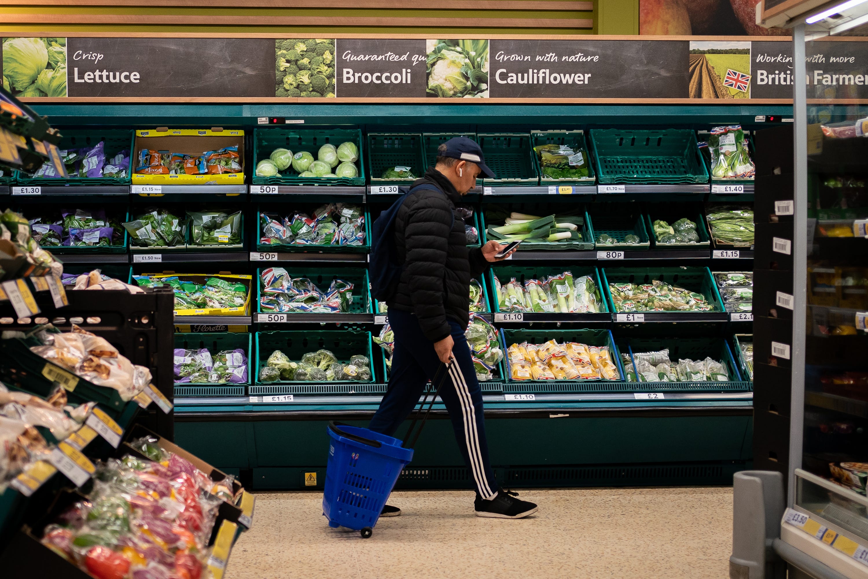 A shopper walking through the salad aisle in a supermarket in south London (PA)