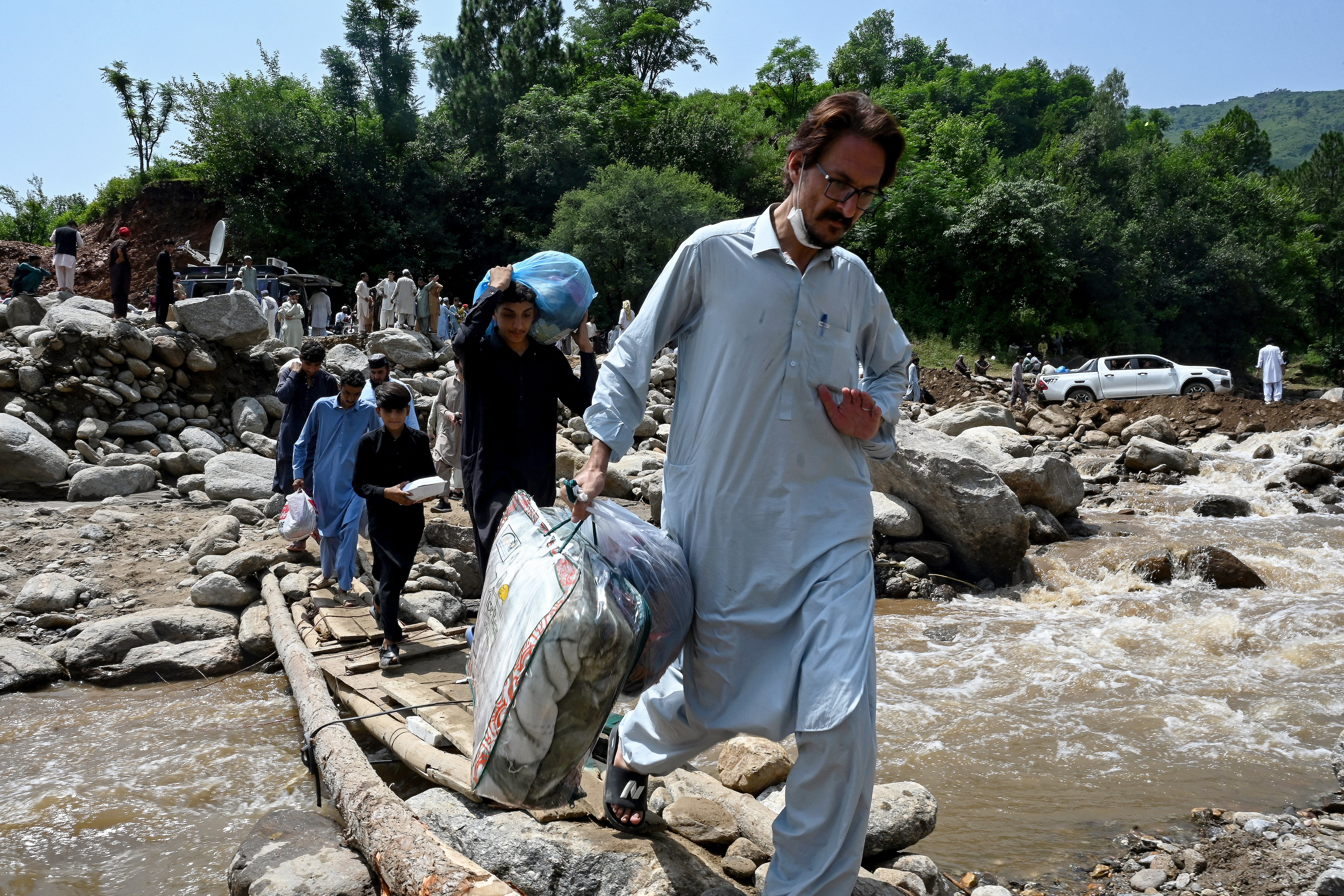 Volunteers carry food, medical and other supplies for flood victims as they cross a river laden with heavy rocks in the Buner district of mountainous Khyber Pakhtunkhwa province