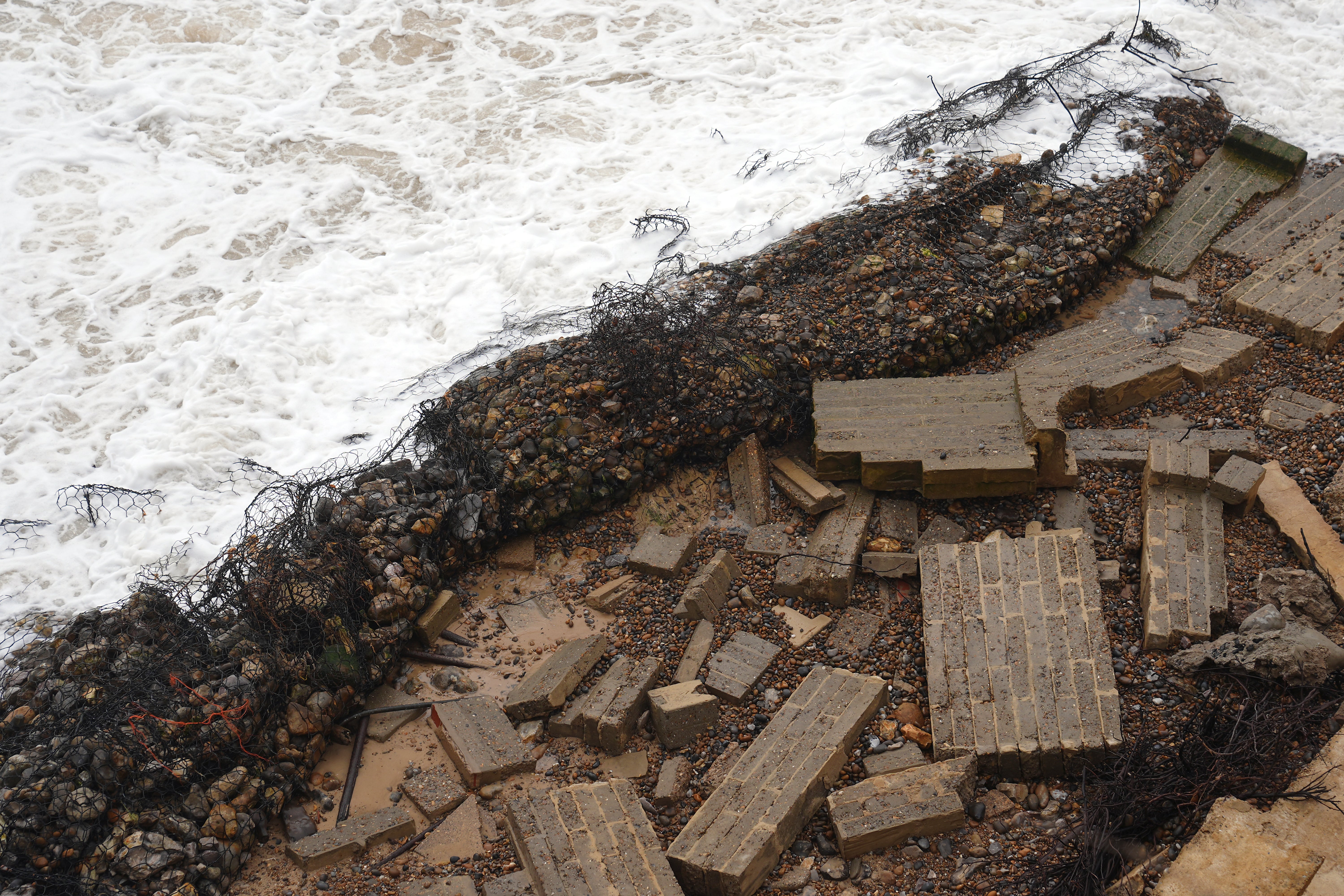 Ms Flick’s former garden wall is seen on the beach below