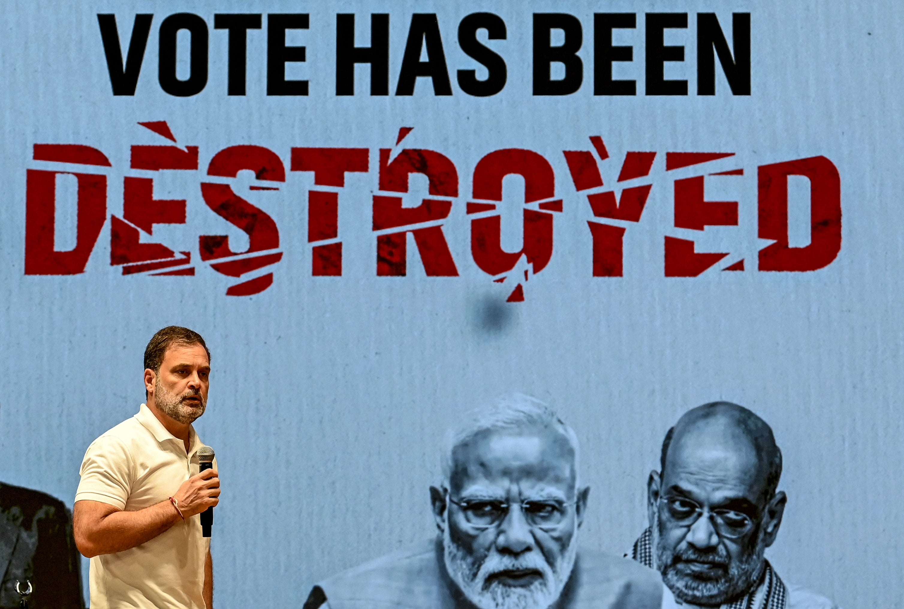Rahul Gandhi addresses the media in front of a screen showing India's PM Narendra Modi (centre) and home minister Amit Shah at the party headquarters in New Delhi