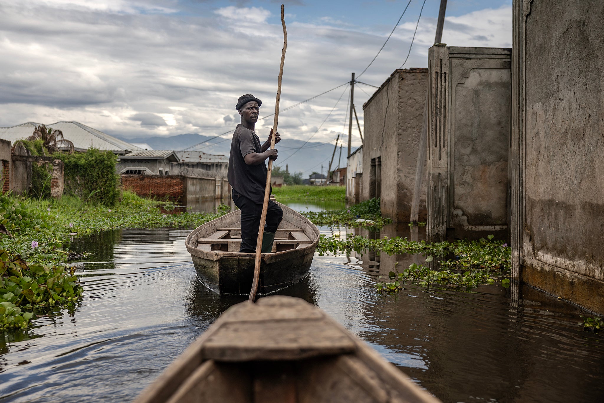 A helmsman uses a long wooden pole to steer his pirogue through a flooded residential area where rising waters from Lake Tanganyika have inundated homes, in the Kinyinya III neighbourhood of Gatumba, in May this year