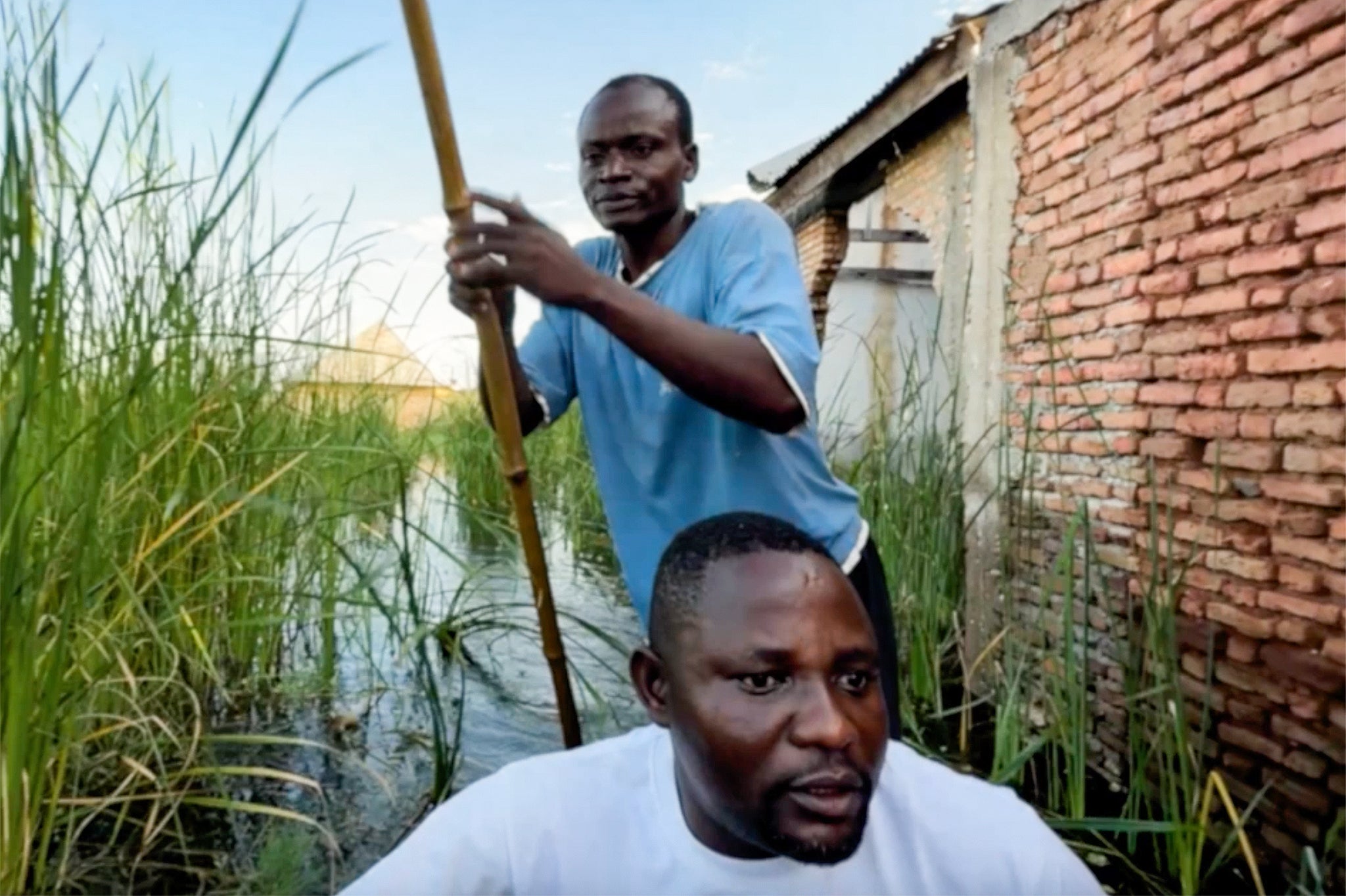 Pastor Jean (front) uses a dugout canoe to access homes that have been flooded by the rising waters of Lake Tanganyika